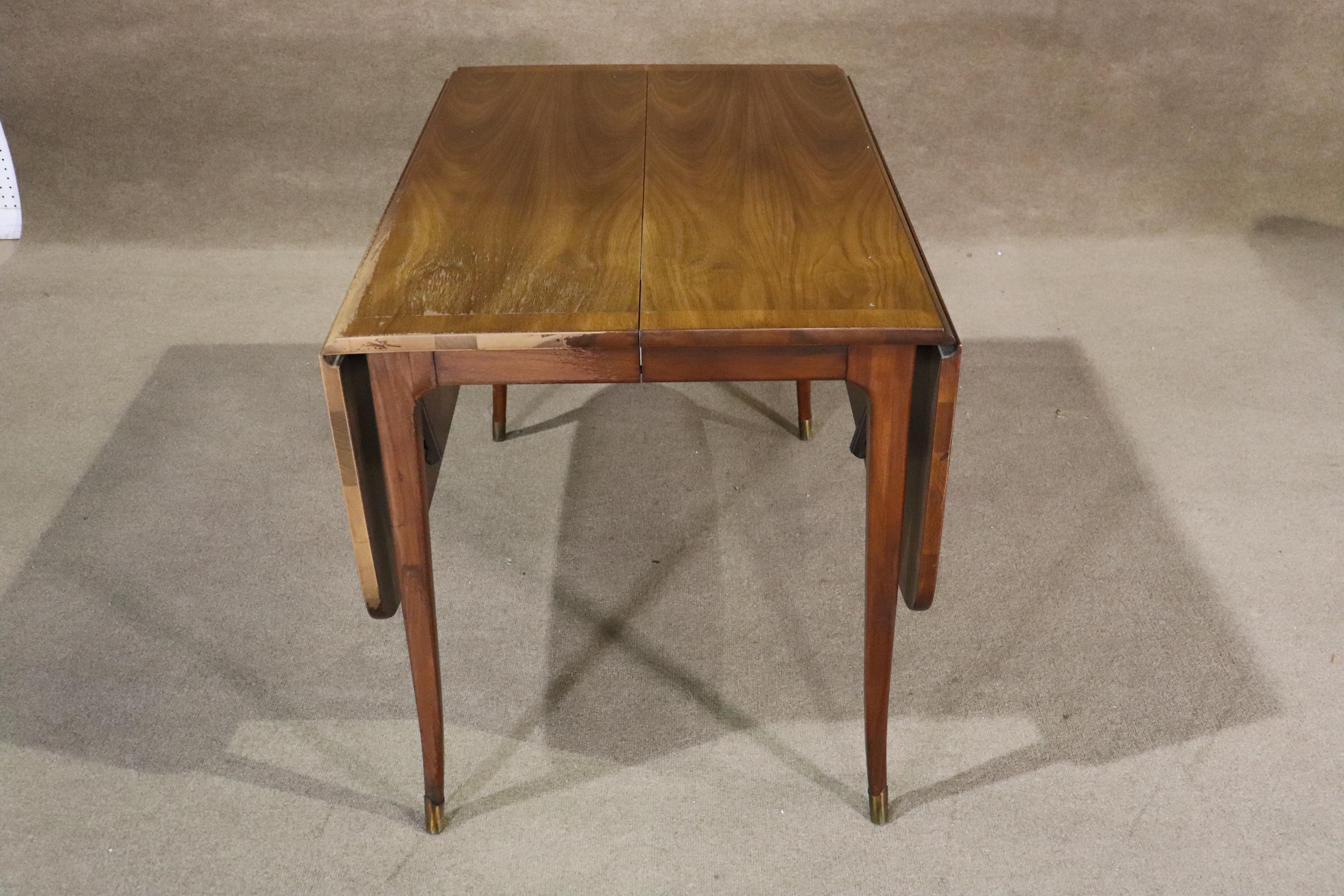 Mid-Century Modern walnut dining table with two drop leaves that open on either side. Three 12 inch leaves will open the table to over 8 feet long. Set on slender brass tipped legs.
Please confirm location NY or NJ.