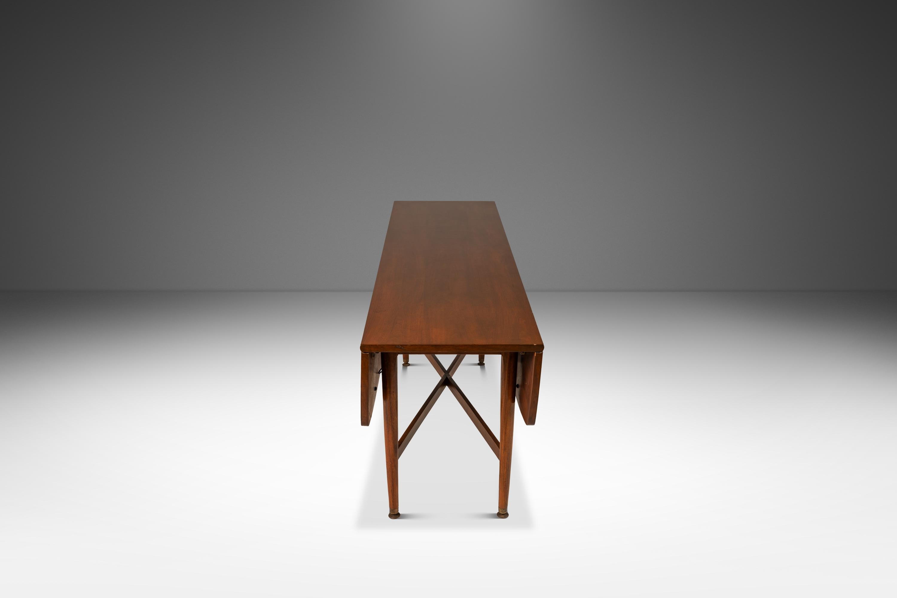 Introducing a drop-leaf dining table designed by the influential Kipp Stewart for Drexel's lauded Declaration Line in the late 1960's. Constructed from a mix of solid and veneered American black walnut this versatile table can easily extend to full