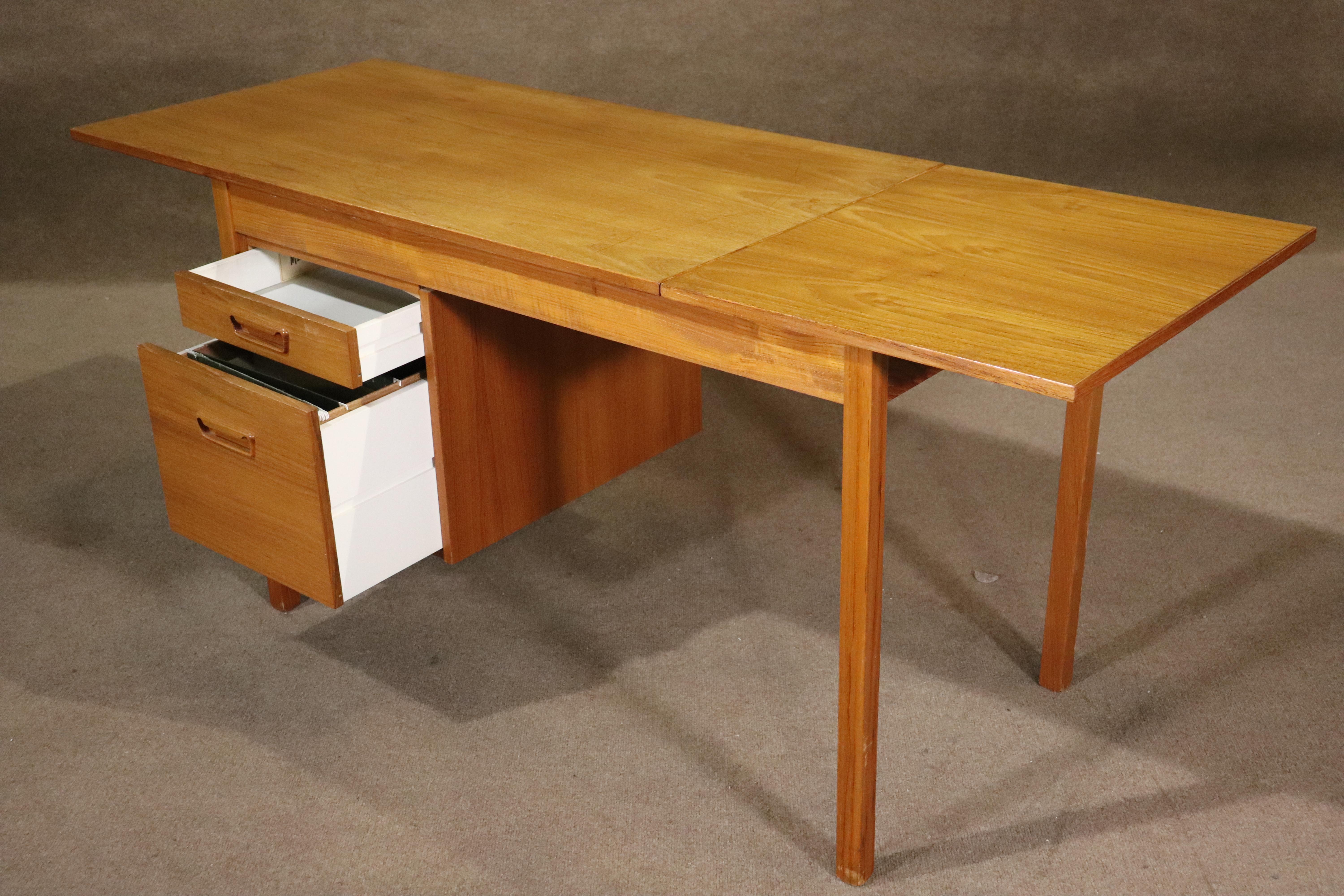 Teak mid-century desk with extra leaf that lifts and slides to extend the desk to 5.5 feet wide. Two drawers, including file size, with inset wood handles.
Please confirm location NY or NJ