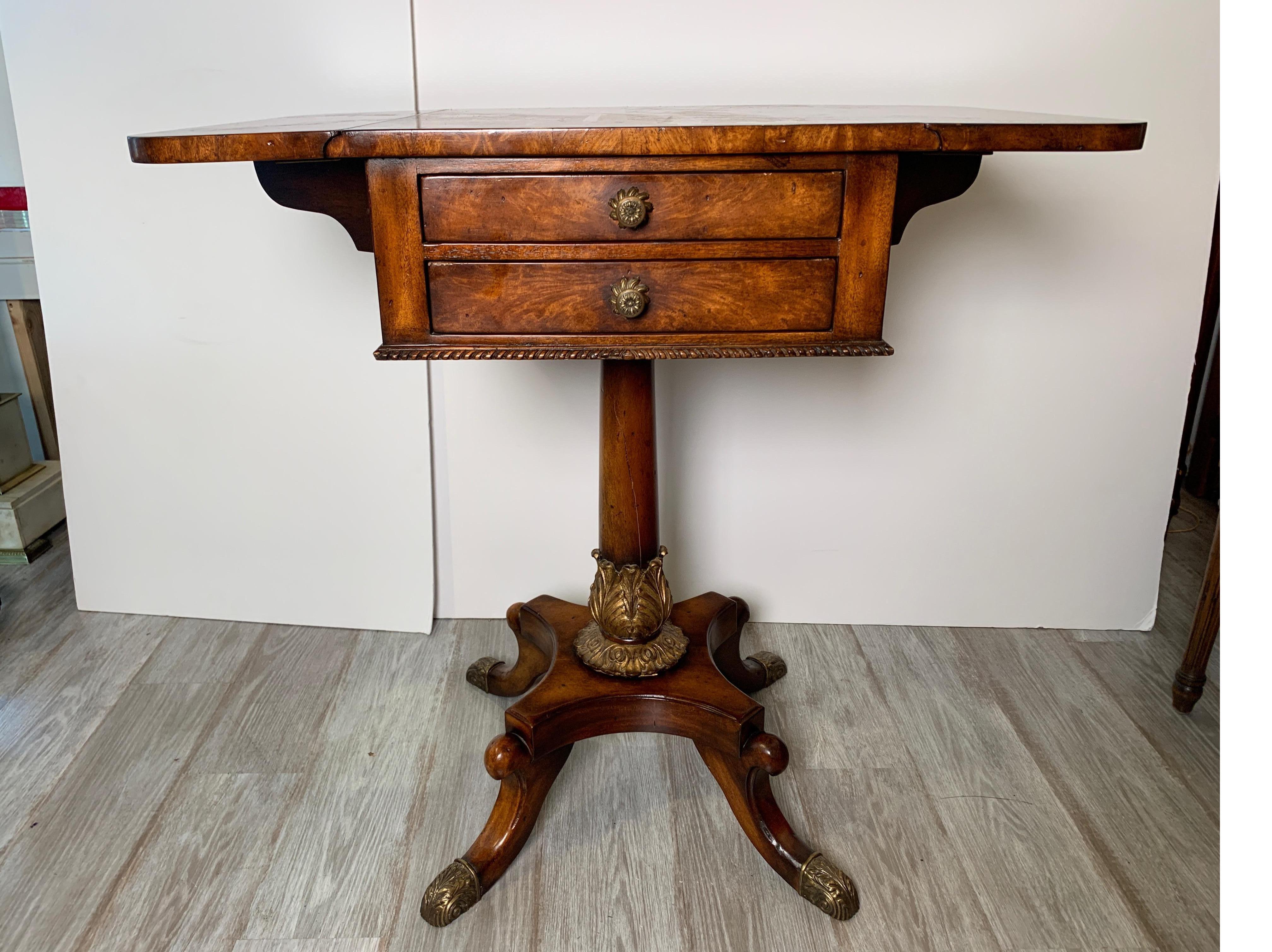 Handsome rich parcel gilt mahogany drop-leaf table with drawers by Theodore Alexander. The top with drop leaves supported by a pedestal column resting on a footed pedestal base.