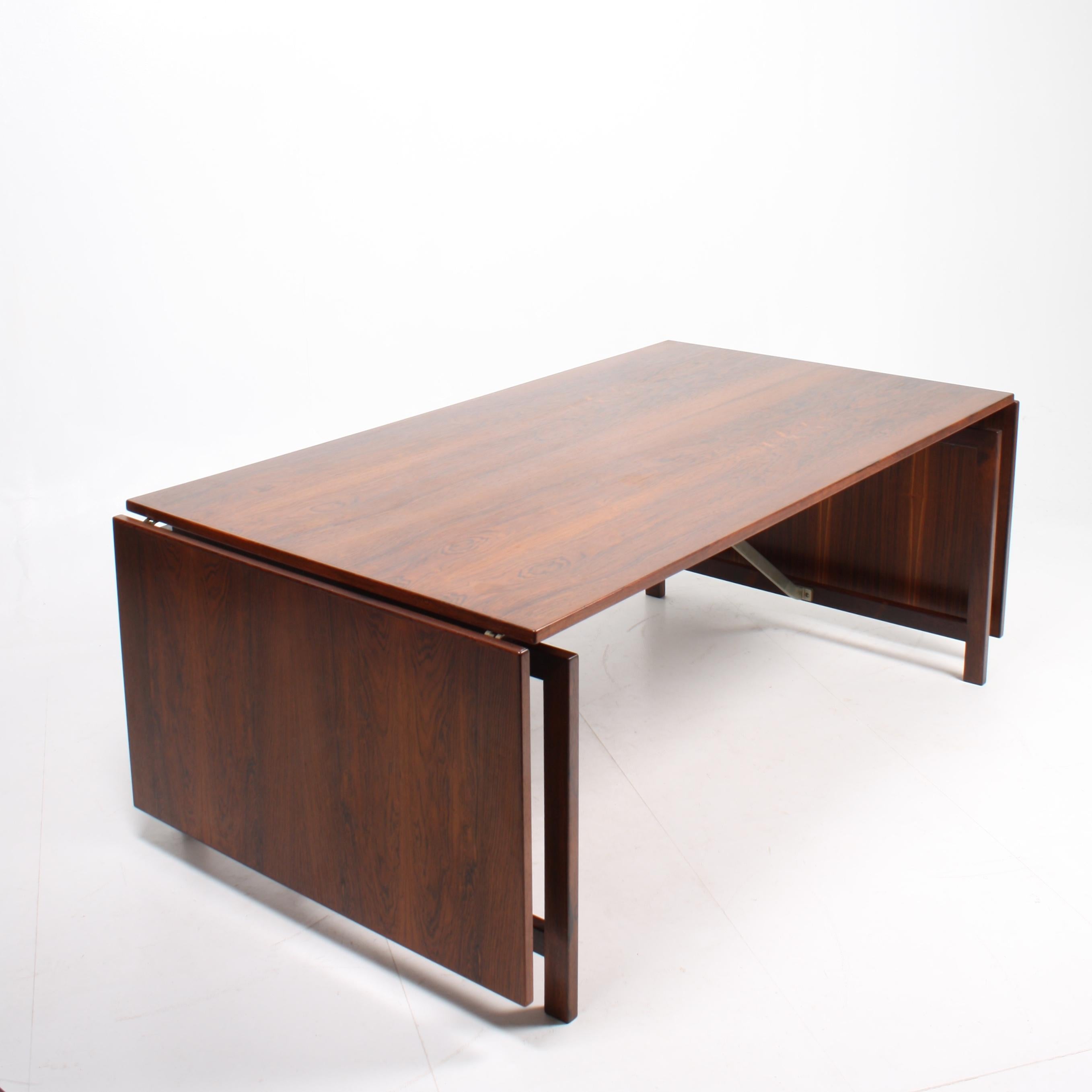 Large drop-leaf table in rosewood with a chromed rail designed by Hans Wegner for Tuck Cabinetmakers. Outstanding quality. Original condition. 180 / 300 cm wide when open.