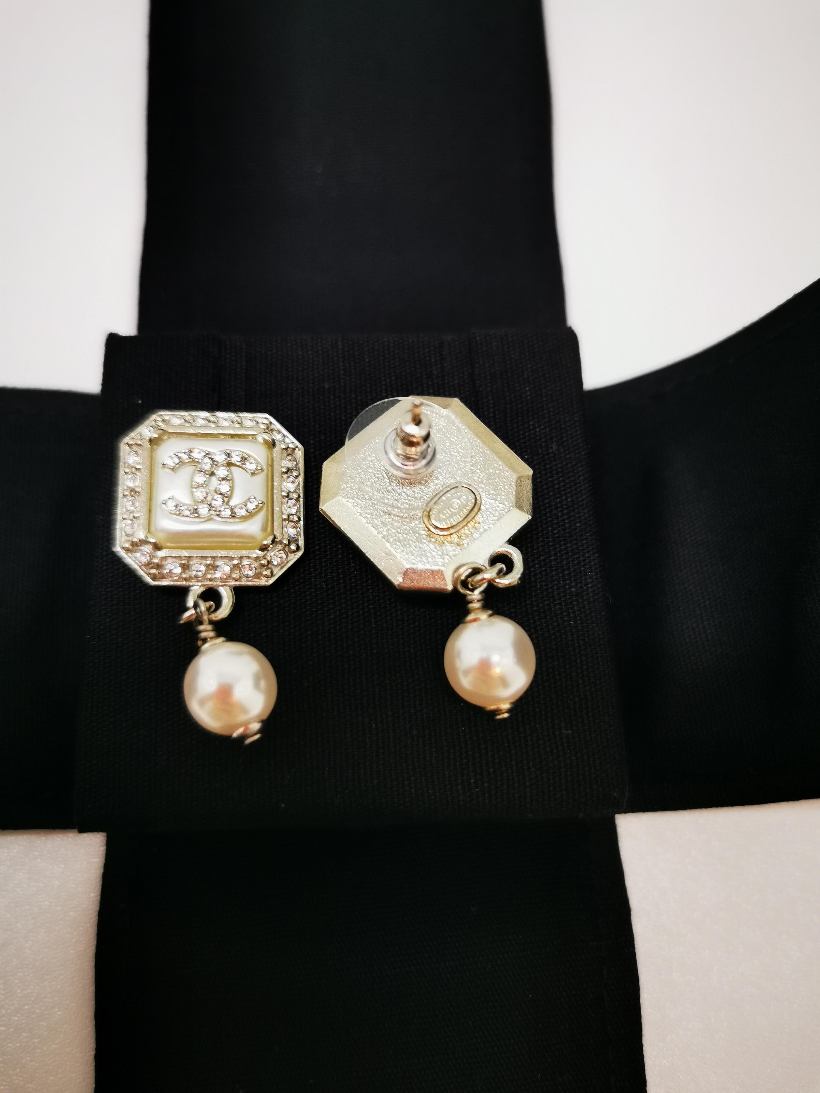 Elevate your style with these stunning Drop Pearl CC Rhinestone Chanel Earrings from the A21 collection. Designed with timeless elegance, each earring features a sophisticated square faux pearl at its center, highlighted by the iconic Chanel CC