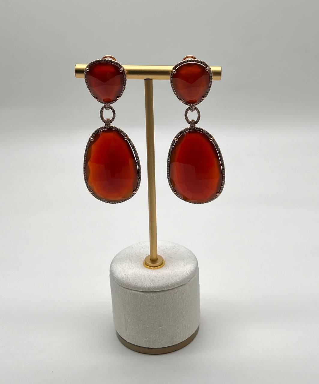 Estos llamativos pendientes presentan atrevidas cornalinas facetadas de color rojo anaranjado, cada una de ellas enmarcada con un delicado borde de brillantes diamantes de acento La piedra superior es un triángulo redondeado, conectado a la