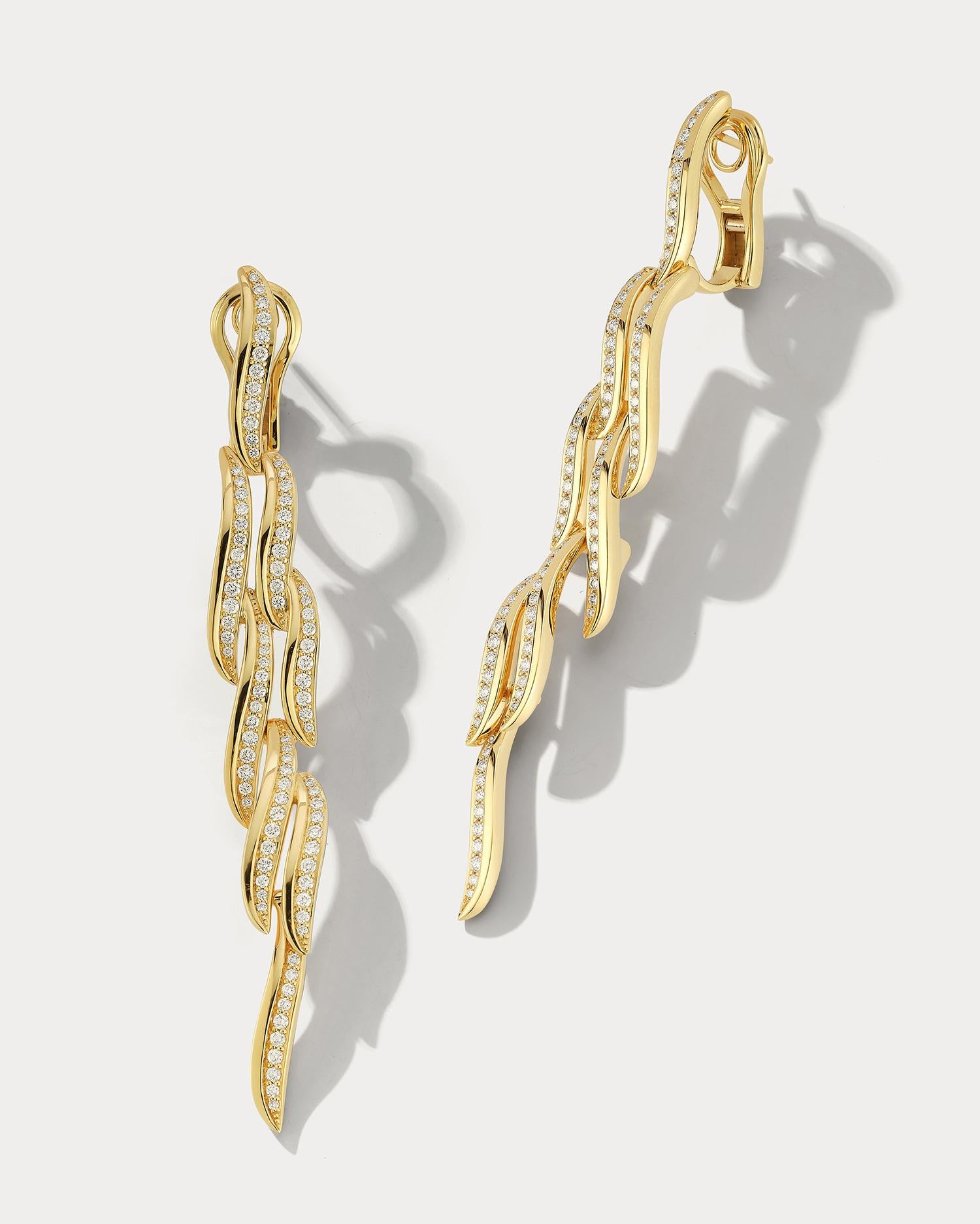 These stunning drop earrings are crafted from high-quality 18k yellow gold and feature a unique wave design with shimmering diamonds. The waves of the design create a fluid and graceful appearance that is truly eye-catching. The diamonds are set in