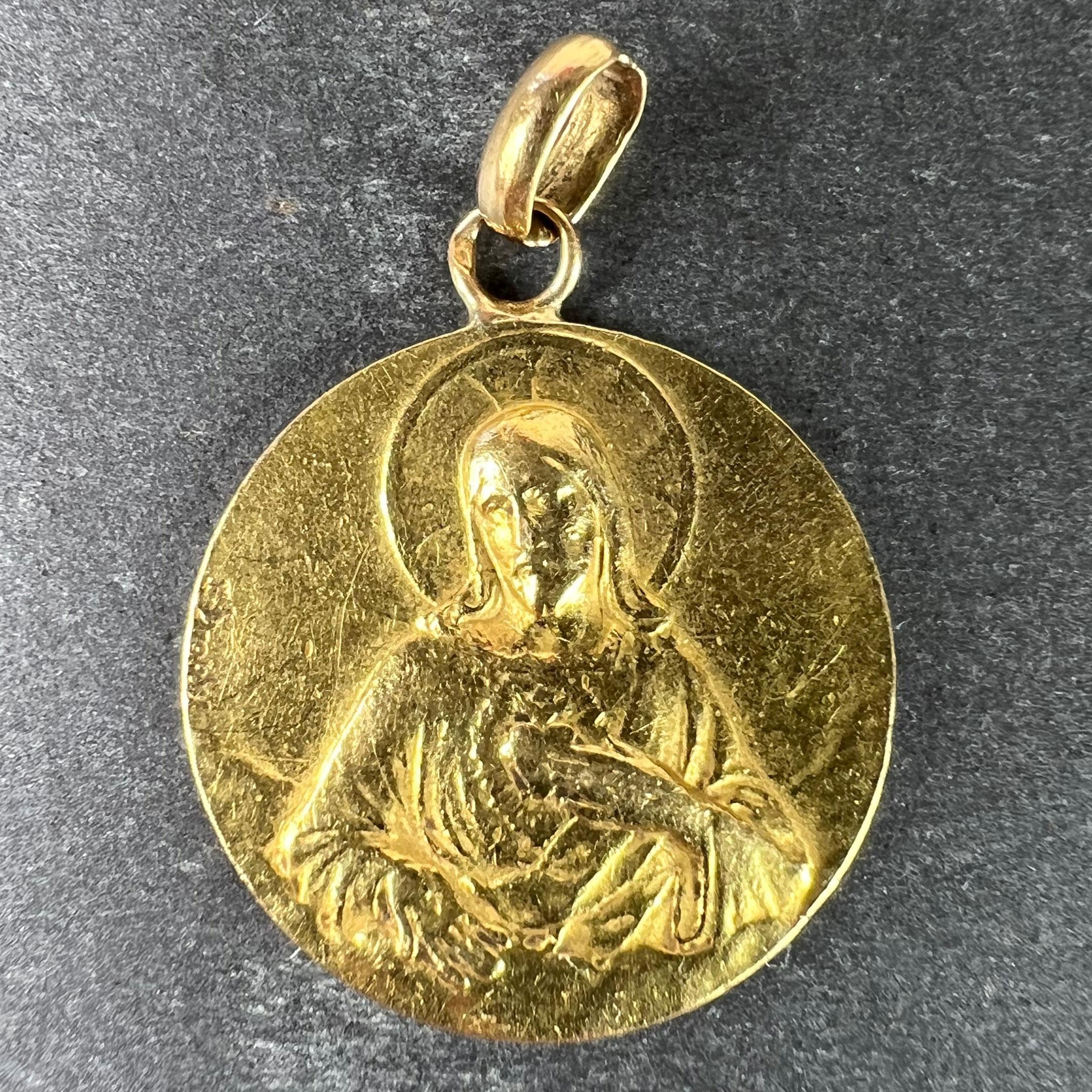 An antique French 18 karat (18K) yellow gold charm pendant designed as a medal depicting the Virgin Mary as the Madonna and Child holding a pair of devotional scapulars, with the phrase Virgo Carmeli surrounding them. The other side depicts Jesus
