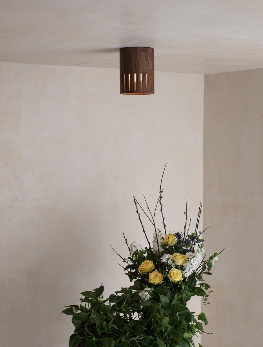 Flush mounted wood cylinder with slits that emits a soft glow.
