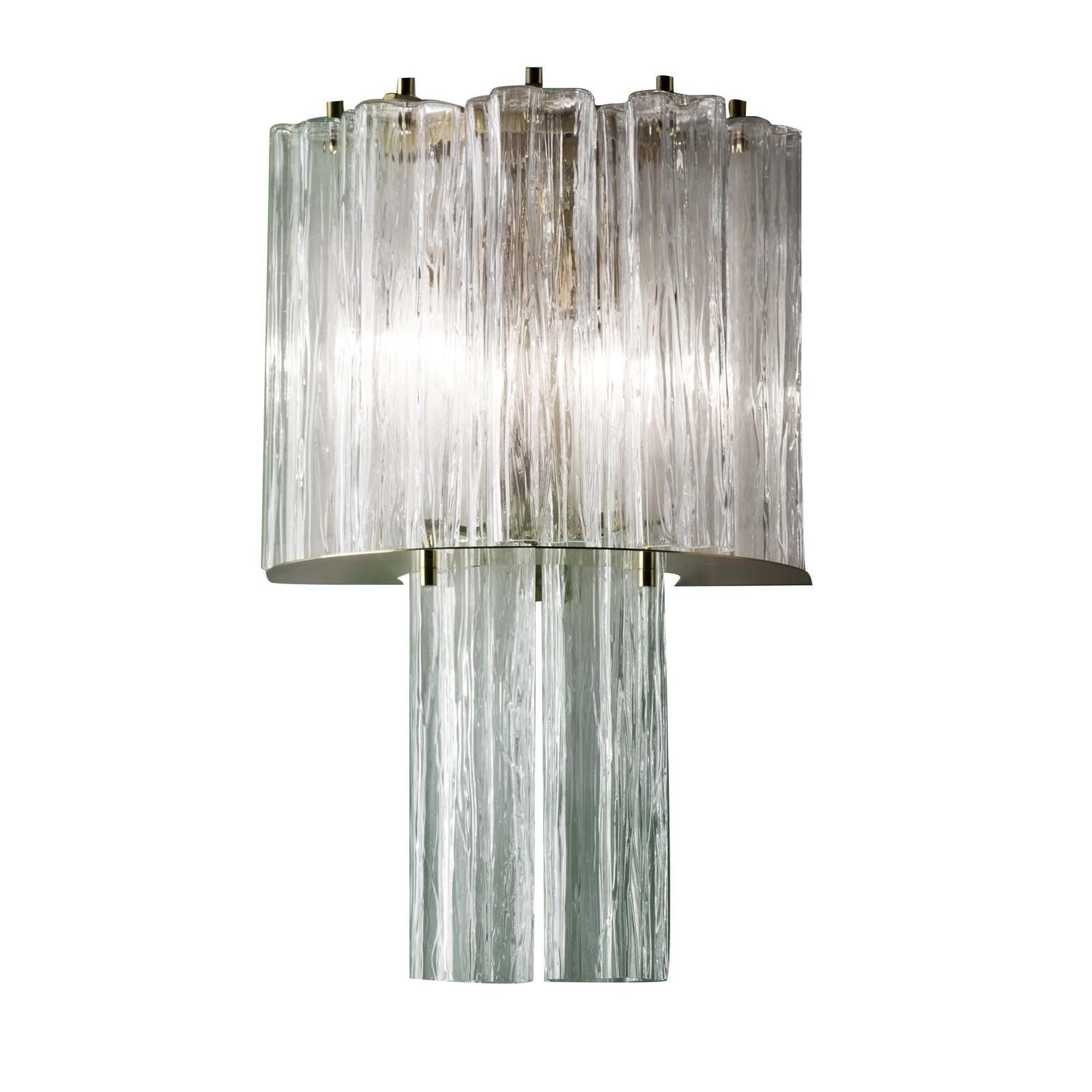 Part of the Home Couture collection, this super sconce is a splendid interpretation of Art Deco glamour. Its structure in metal with a brass finish creates two layers of diffusers in glass that create the effect of a precious jewel mounted on the