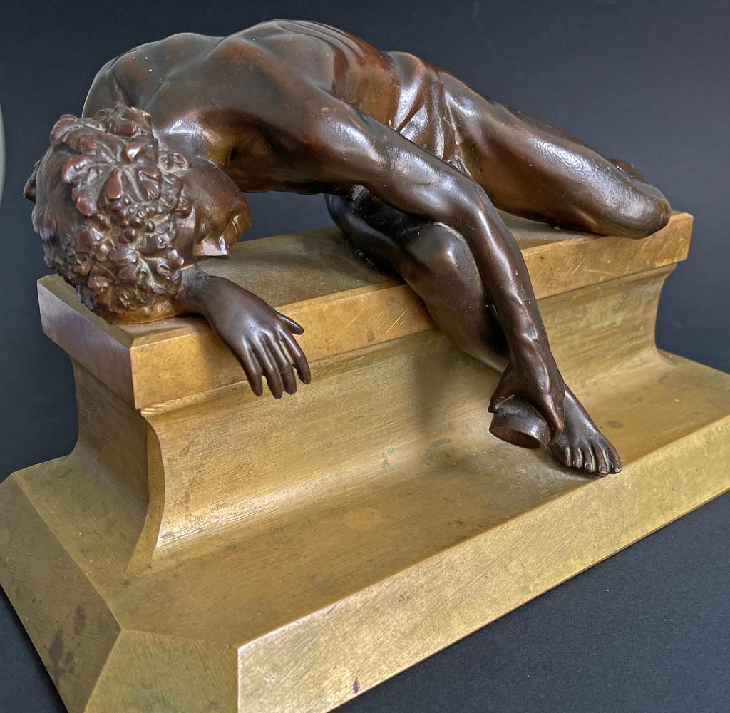 This rare and beautiful bronze depicts Bacchus or Dionysus, his limbs all akimbo, asleep atop a gilded bench, his left arm holding an empty wine cup, clearly exhausted after a night of revelry. Although best known as the god of wine, Bacchus was
