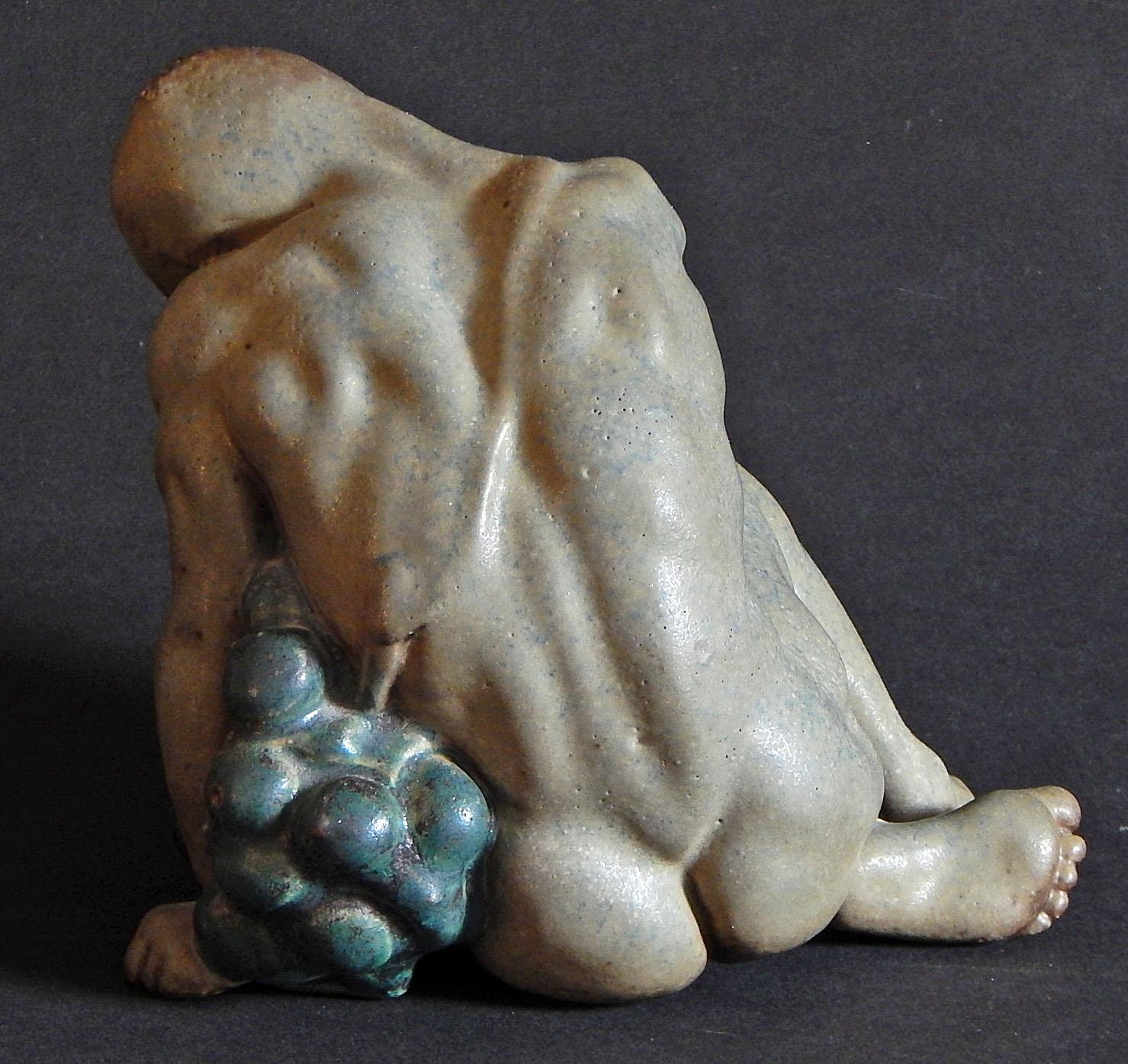 This sensuous ceramic piece depicts a beautifully sculpted nude figure embracing an exaggerated grape cluster, sculpted by Kai Nielsen for Bing & Grondahl in Copenhagen. While all examples of this piece are rare, the glazes here are especially