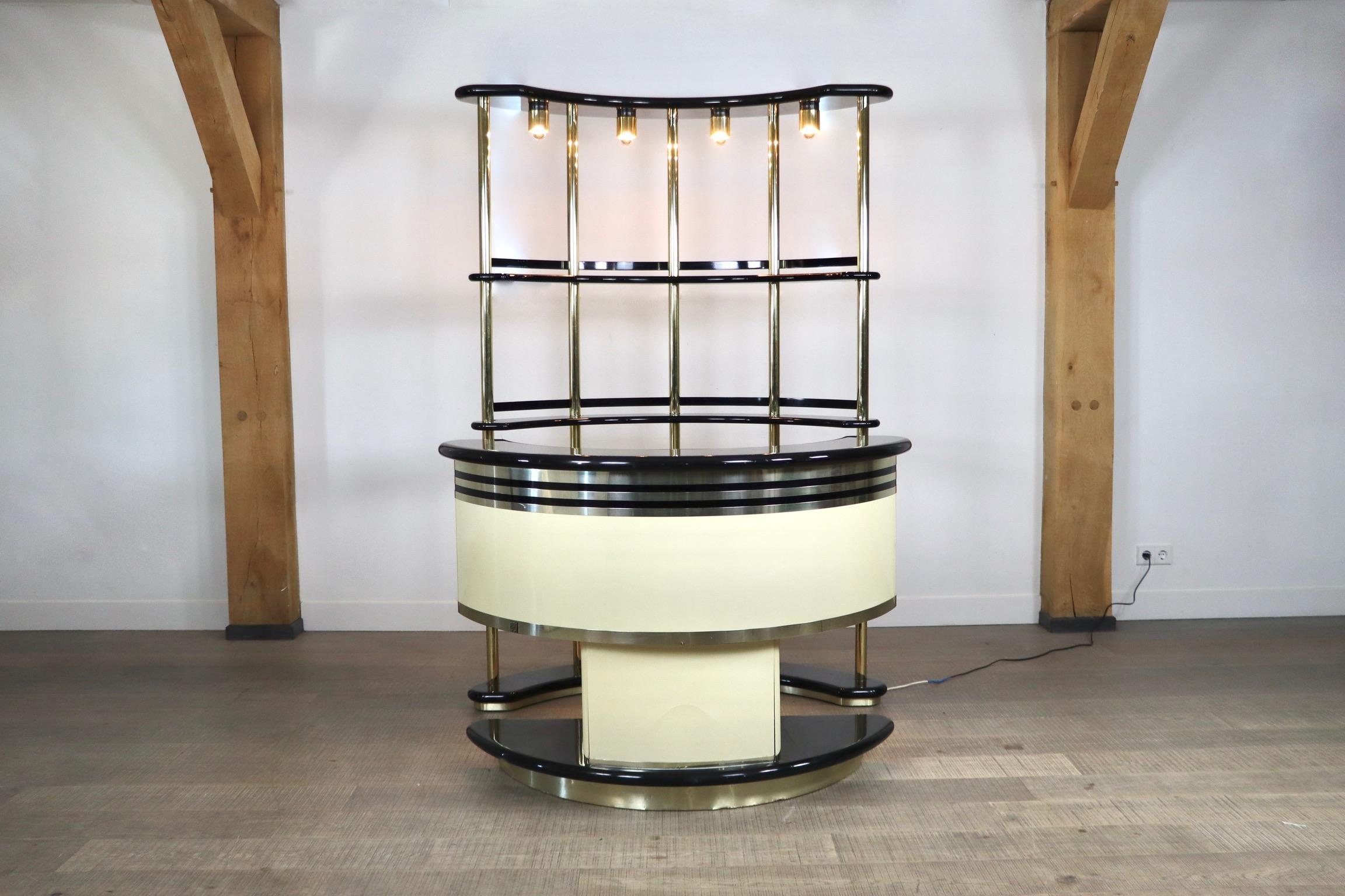 Stunning Gold and black Dry Bar by Guzzini for Stilglass Donati, Italy 1970s. The bar is composed of two pieces: A counter with a half round mirror which contains a working refrigerator and two glass doors to store your cocktail glasses etc. in, a