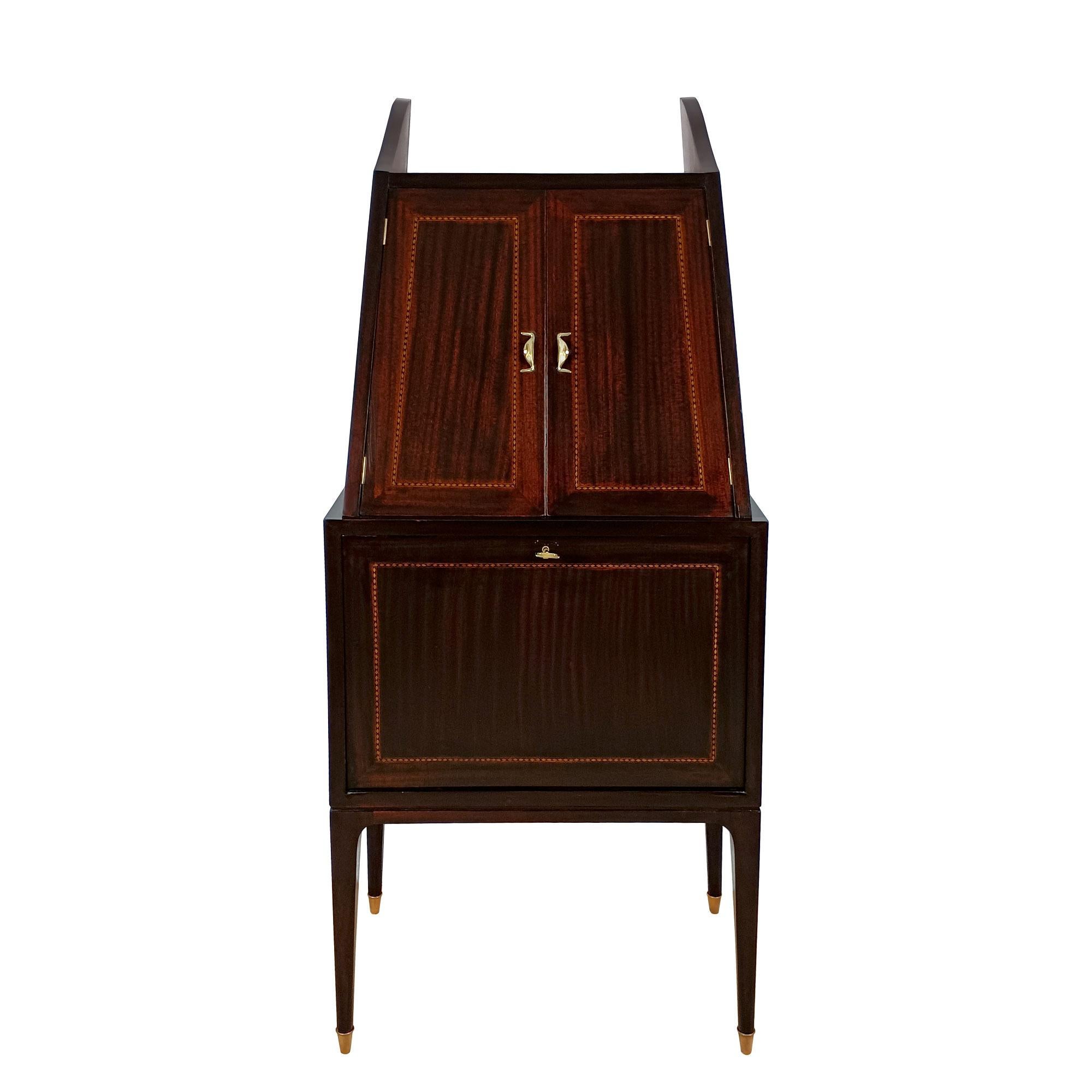 Dry bar, wood with mahogany veneer, decorated with a maple and ebony marquetry border, opening on two maple compartments. Polished brass handles and feet.
Italy circa 1940