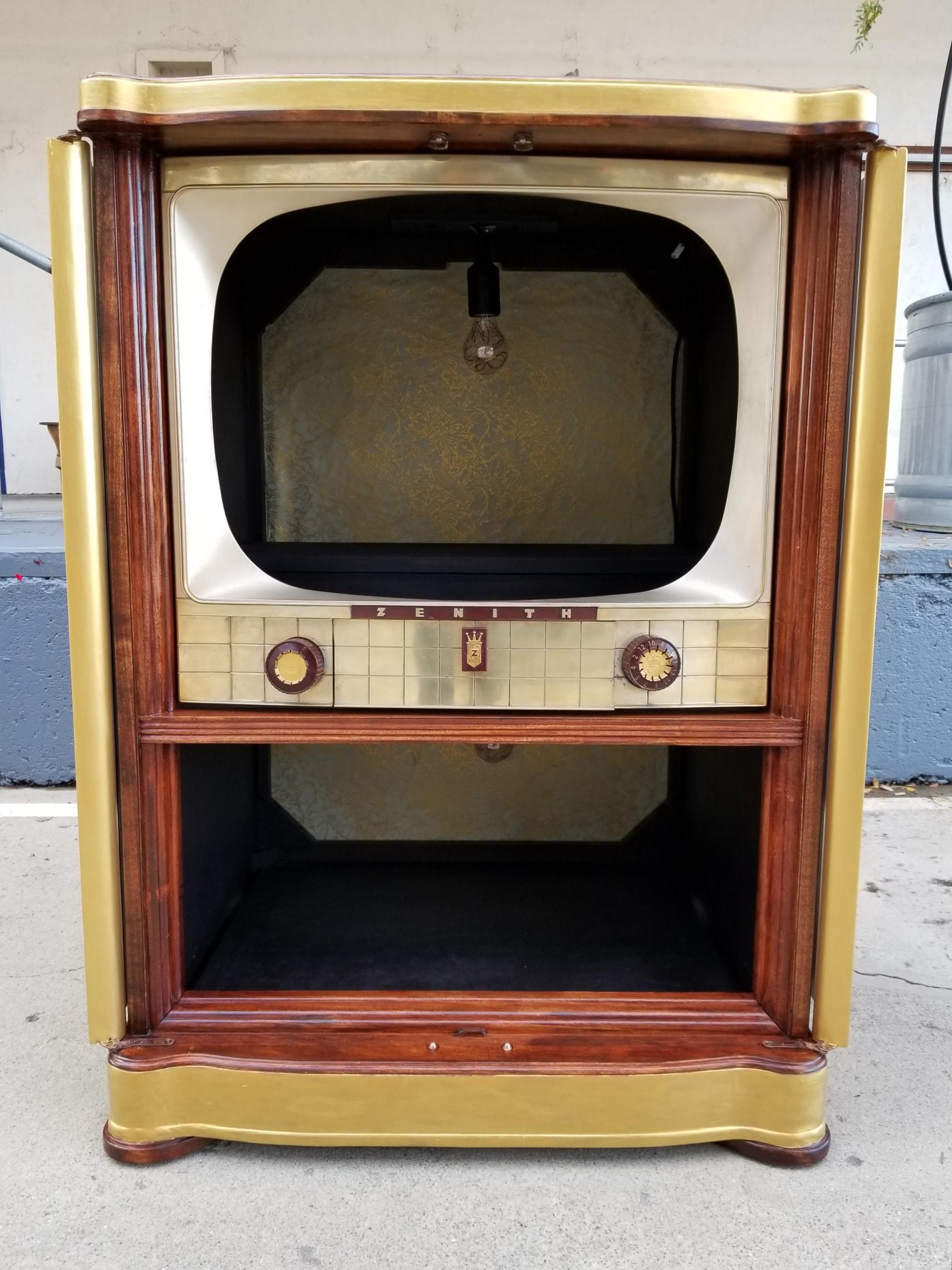 Unique repurposed Zenith television set bar conversion. Beautiful 1950s ribbon cut mahogany TV cabinet converted to a dry bar. Upper and lower storage areas have electric single bulb illumination. Double door access with doors folding to sides of