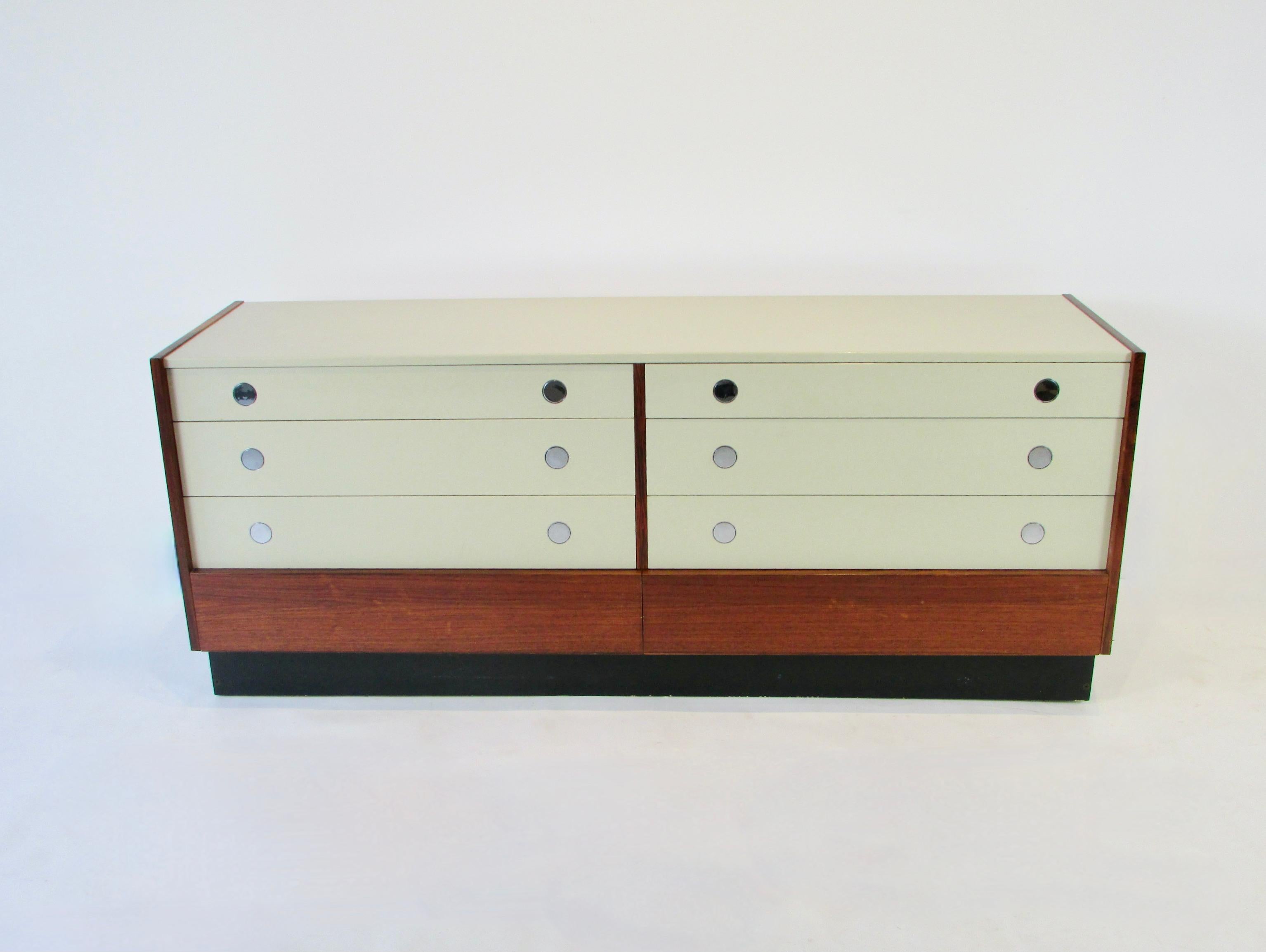 Eight drawer double dresser by Drylund. Original label inside top drawer. Rosewood cabinet holds two rows of three lacquered drawers over a lower rosewood drawer. Upper drawers have chrome disc drawer pulls that turn horizontally as you touch them.