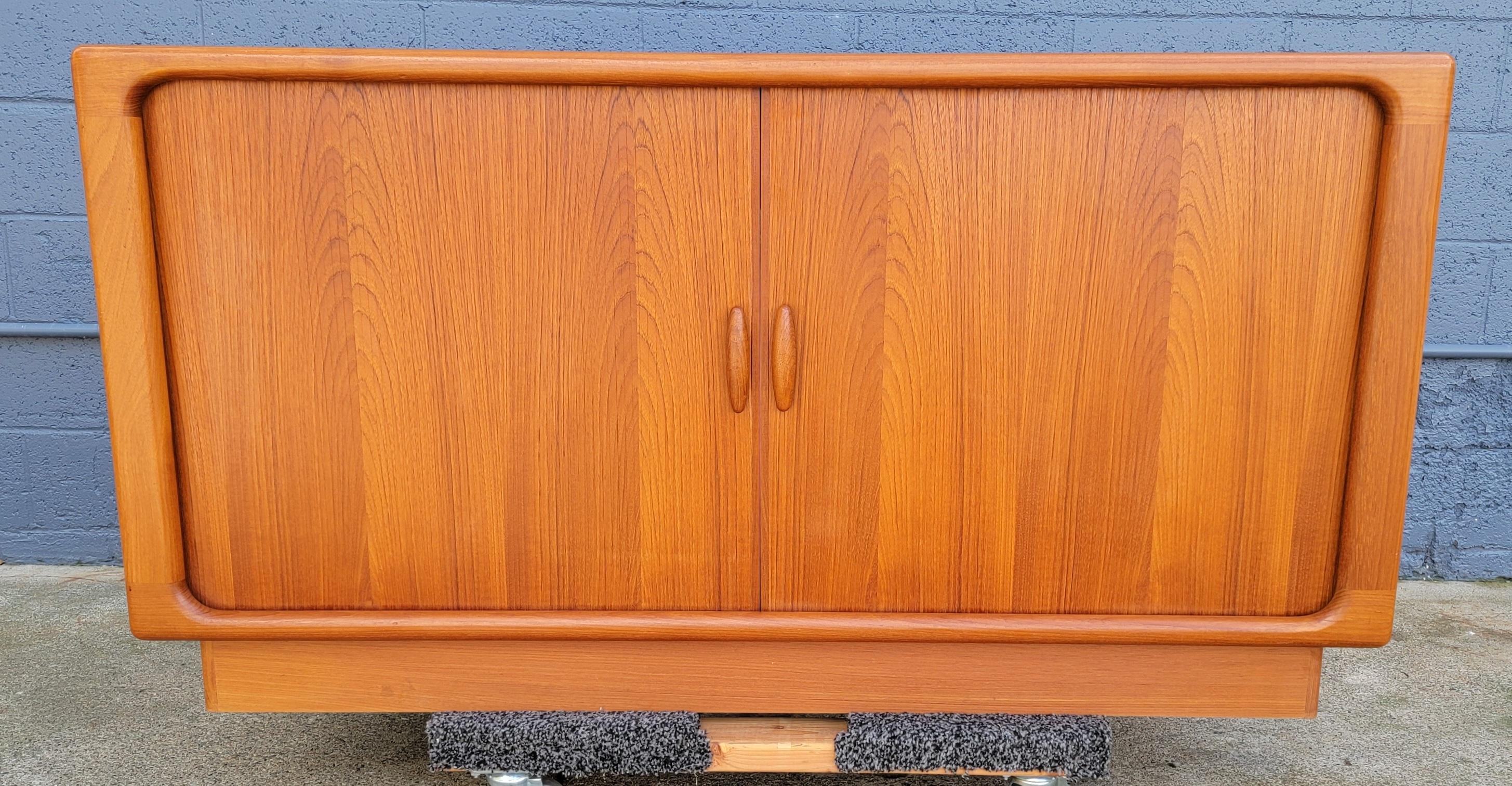 Classic teak Danish Modern credenza with a fitted interior and sliding Tambour doors. Exceptional original condition and finish. Crafted by Dyrlund Furniture of Denmark. Book-matched wood grain construction. Substantial credenza with fine