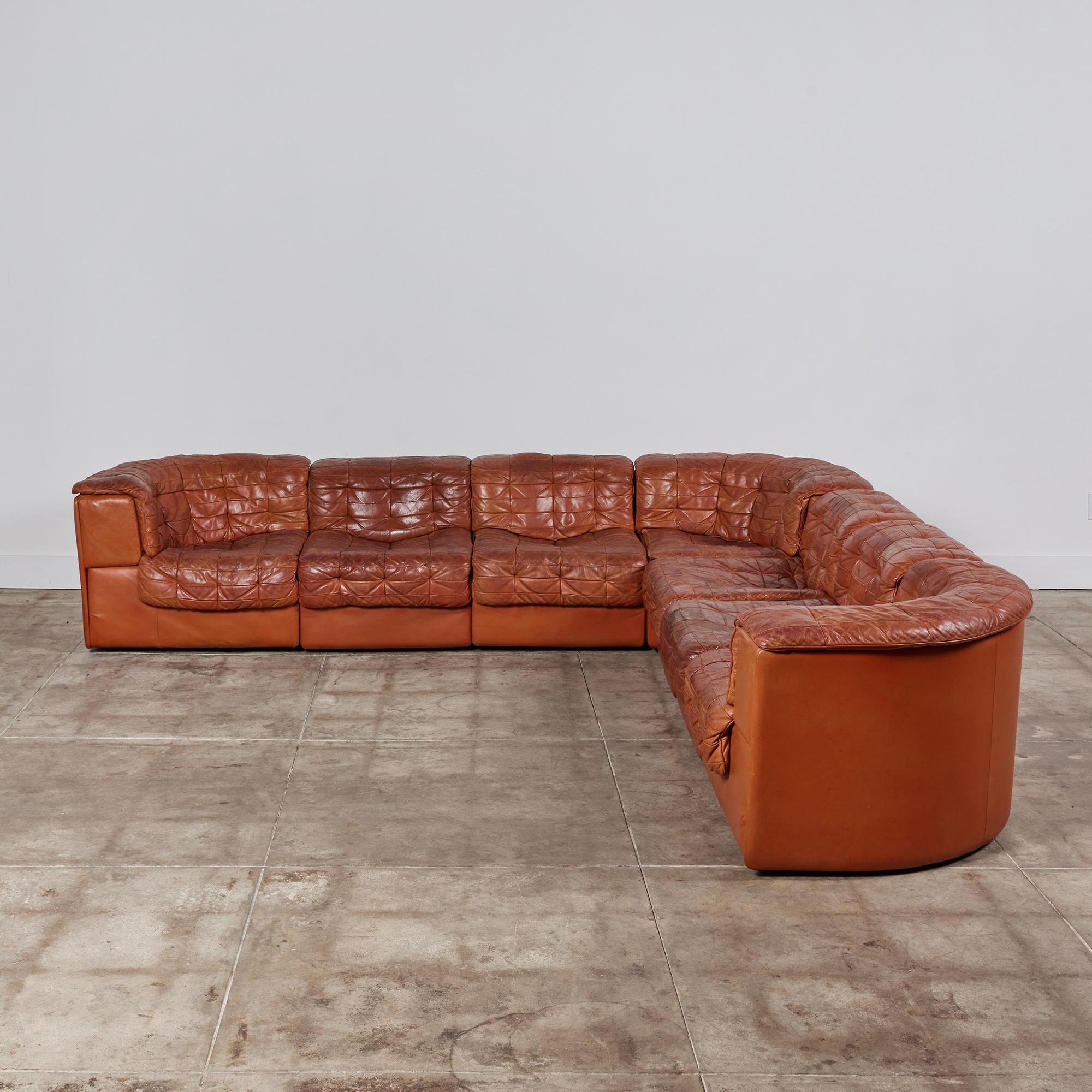 DS-11 cognac colored leather sofa circa 1970s, for De Sede, Switzerland. The modular system consists of three corner seats and four center seats all upholstered in the original perfectly patinated leather patchwork upholstery. It can be arranged as