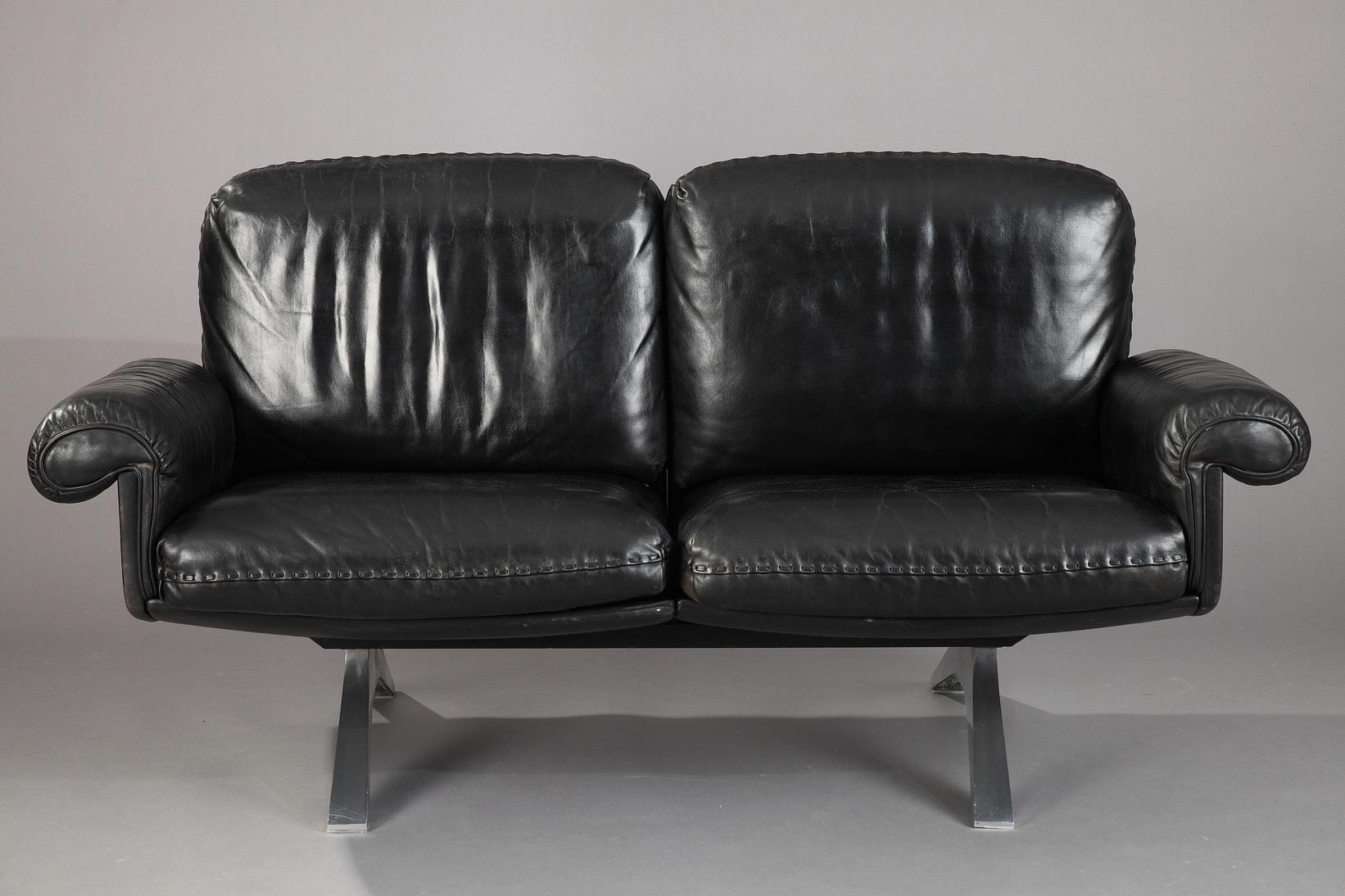 Retro De Sede DS 31 living room set composed of a two-seat sofa and a swivel lounge armchair with its ottoman. Manufactured in the 1970s by De Sede craftsman from Switzerland, these pieces are in soft black leather upholstery, with chrome-plated