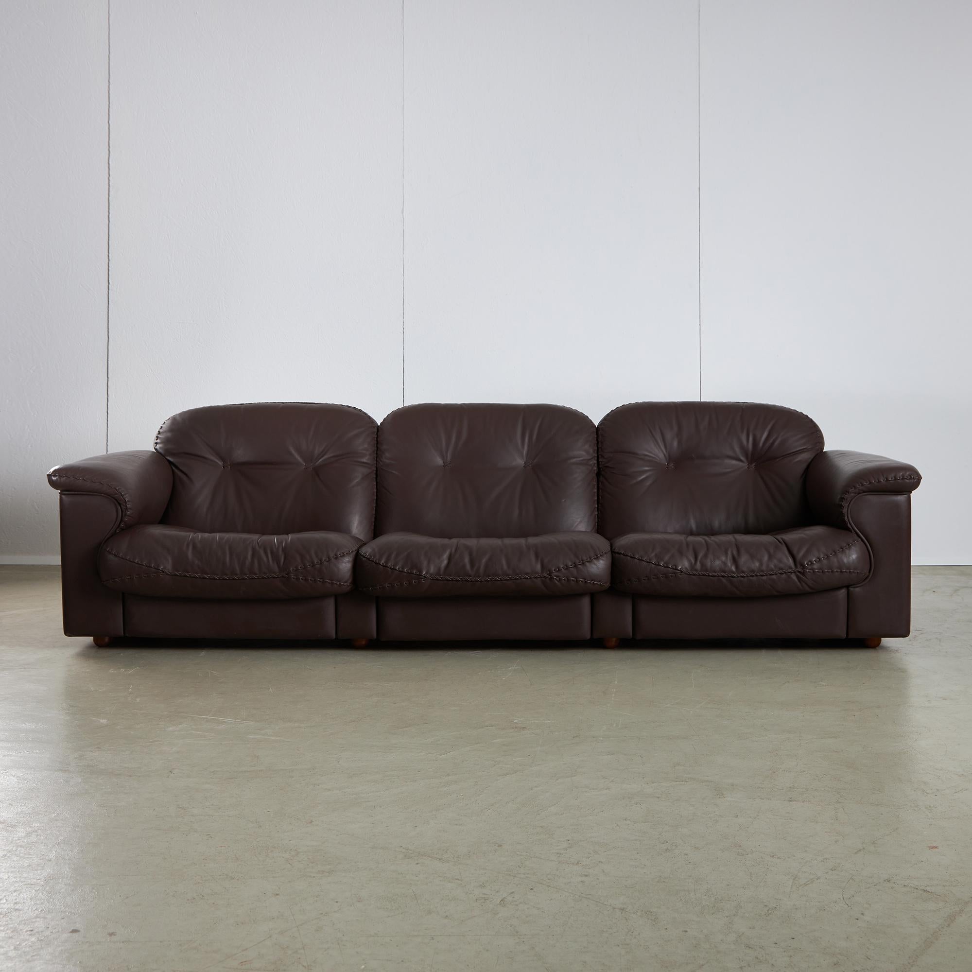 Three-seater brown leather DS101 3 sofa designed for De Sede, with hand-stitched seams and extendable individual seats for lounge sitting. Under the cushions you can find Zani Italia upholstery showing small tears and marks. 