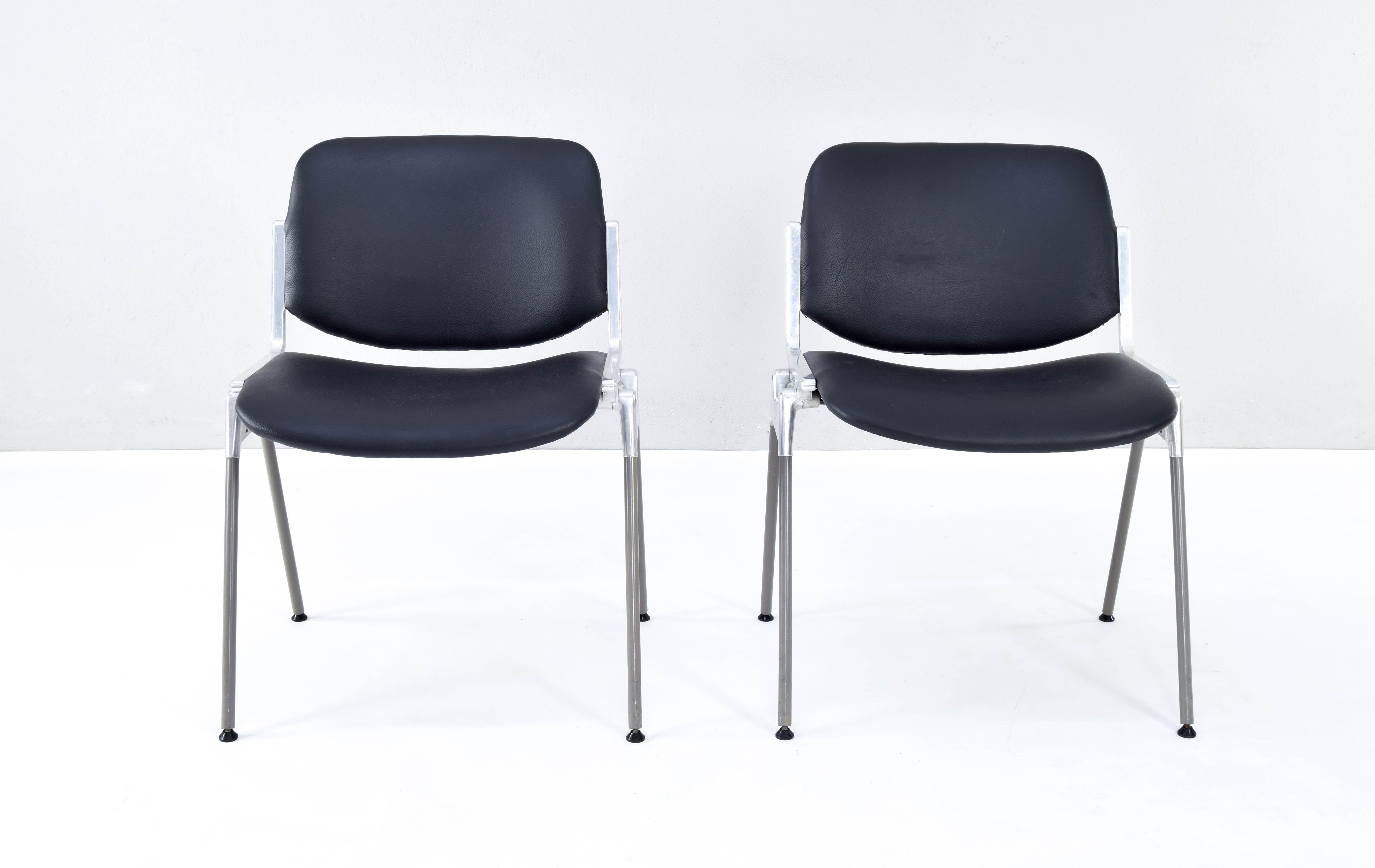 Set of two stackable chairs model DSC 106 designed by Giancarlo Piretti in 1965 and produced by the Italian firm Castelli. 
Aluminum and steel structure, original upholstery in black synthetic leather in good condition.
Measurements:
High 77