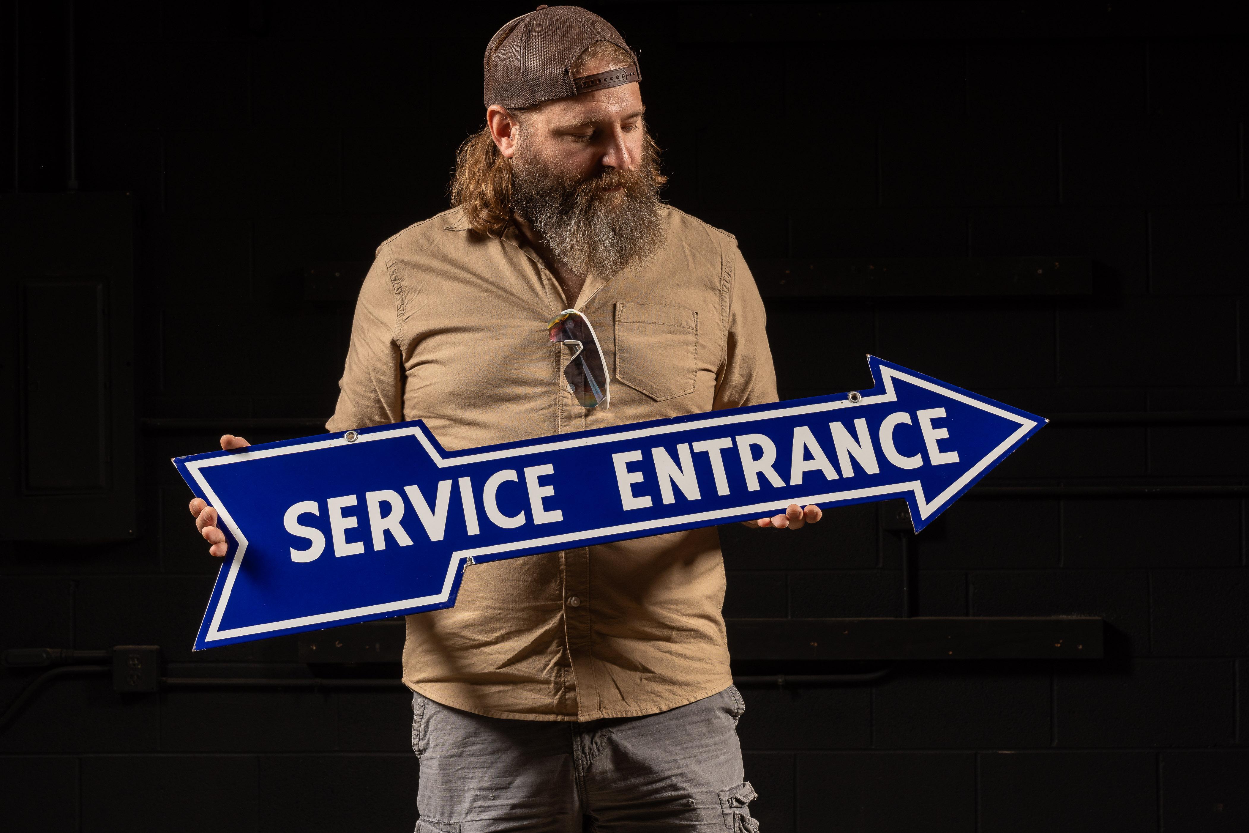 Double-sided porcelain directional arrow sign.

This piece features white block text over a royal blue arrow, creating a high-contrast item; also present are two grommets for fastening/mounting.