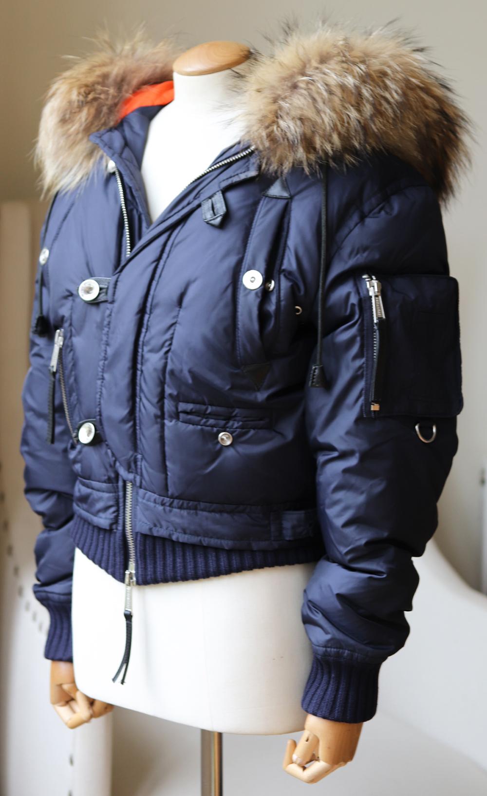 Cut from down, this jacket has a raccoon-fur trim hood and is lightly padded with down to fit a bomber jacket style.
There are discreet ribbed knit thick hems and cuffs for a warm fit.
Navy down, beige and brown fur (Raccoon).
Zip and button