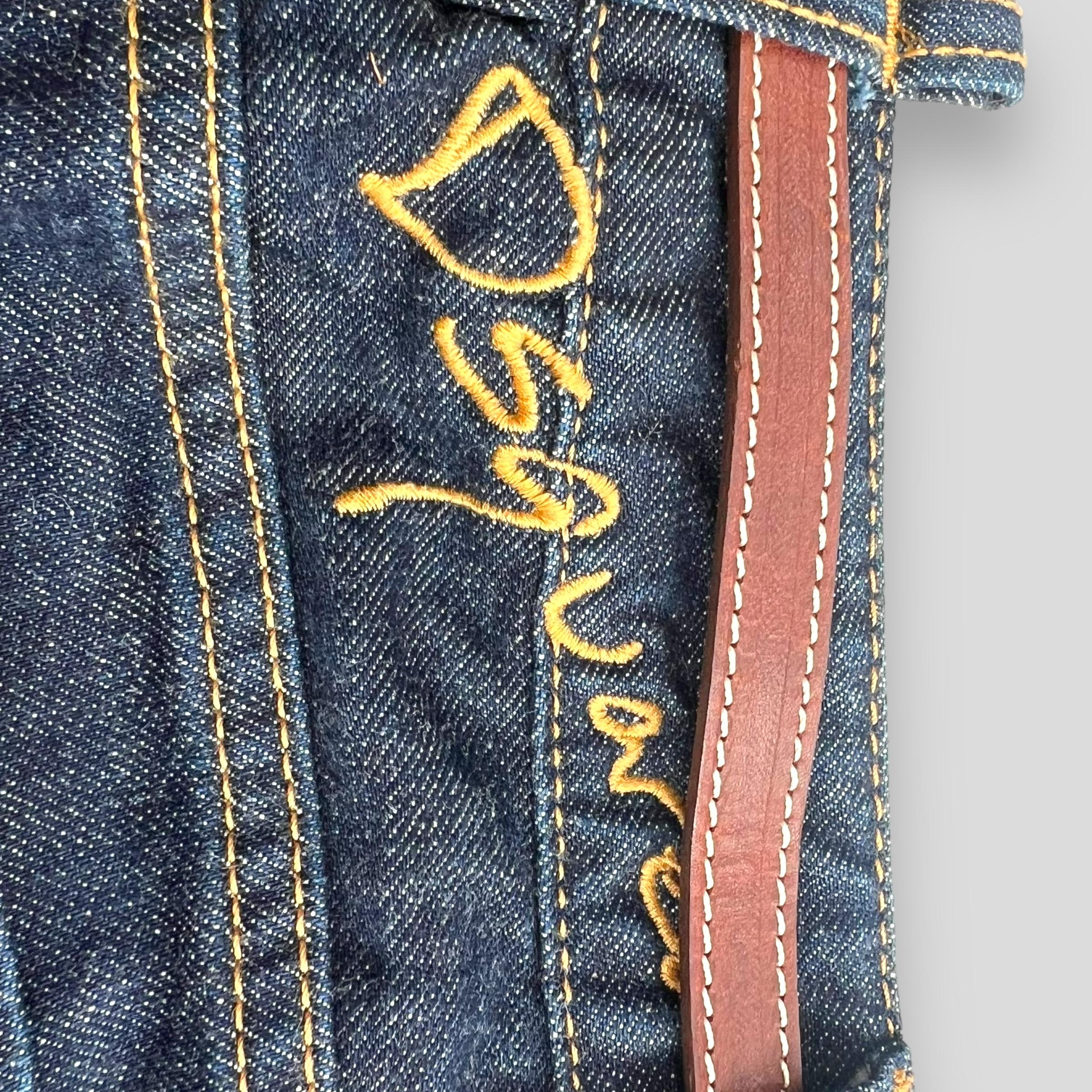 Dsquared2 2003 Denim-Rock mit Mikrogürtel 

Dieser F/W 2003 Bondage-Minirock besteht aus dunkel gewaschenem Jeansstoff mit einem Reißverschluss an der Vorderseite und verstellbaren Riemen aus braunem Leder, die mit goldenen Ringen verziert sind und