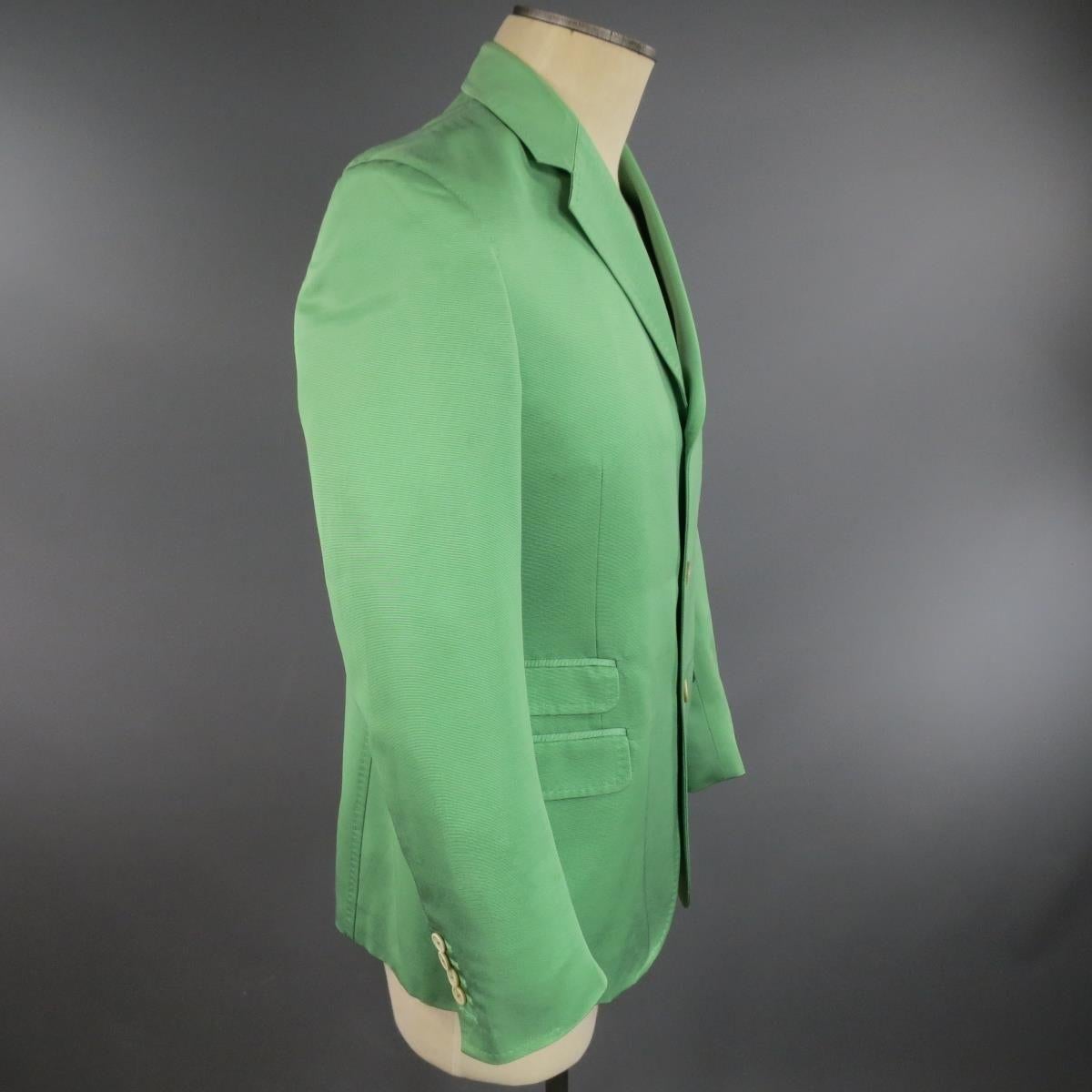 DSQUARED2 sport coat comes in light green cotton silk blend ribbon textured faille fabric with a three button closure, notch lapel, triple flap pocket front, functional button sleeves, single back vent and top stitching detail throughout. Made in