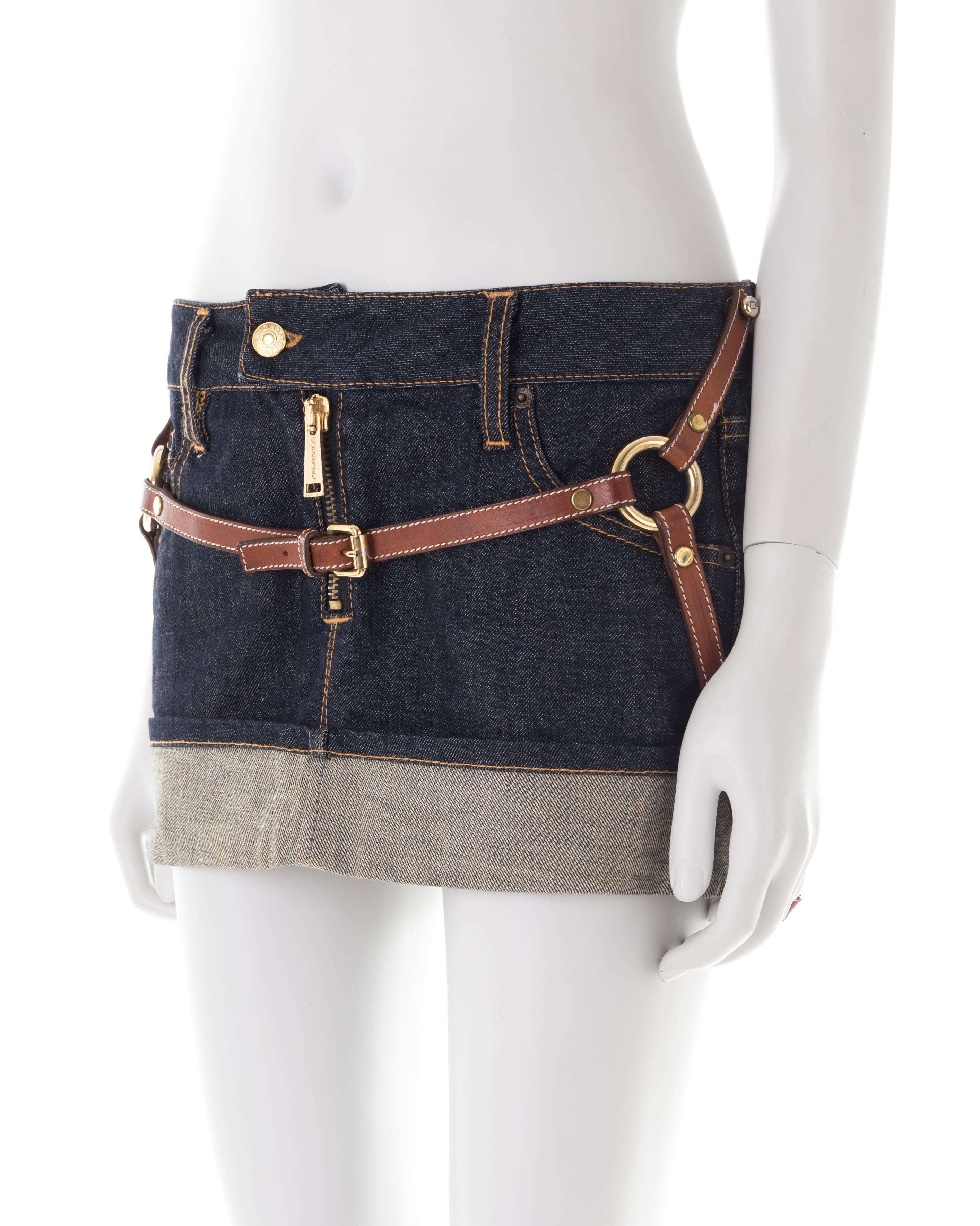 - Dark wash denim mini skirt
- Front zipper
- Brown leather adjustable straps with golden rings
- Bottom cuff
