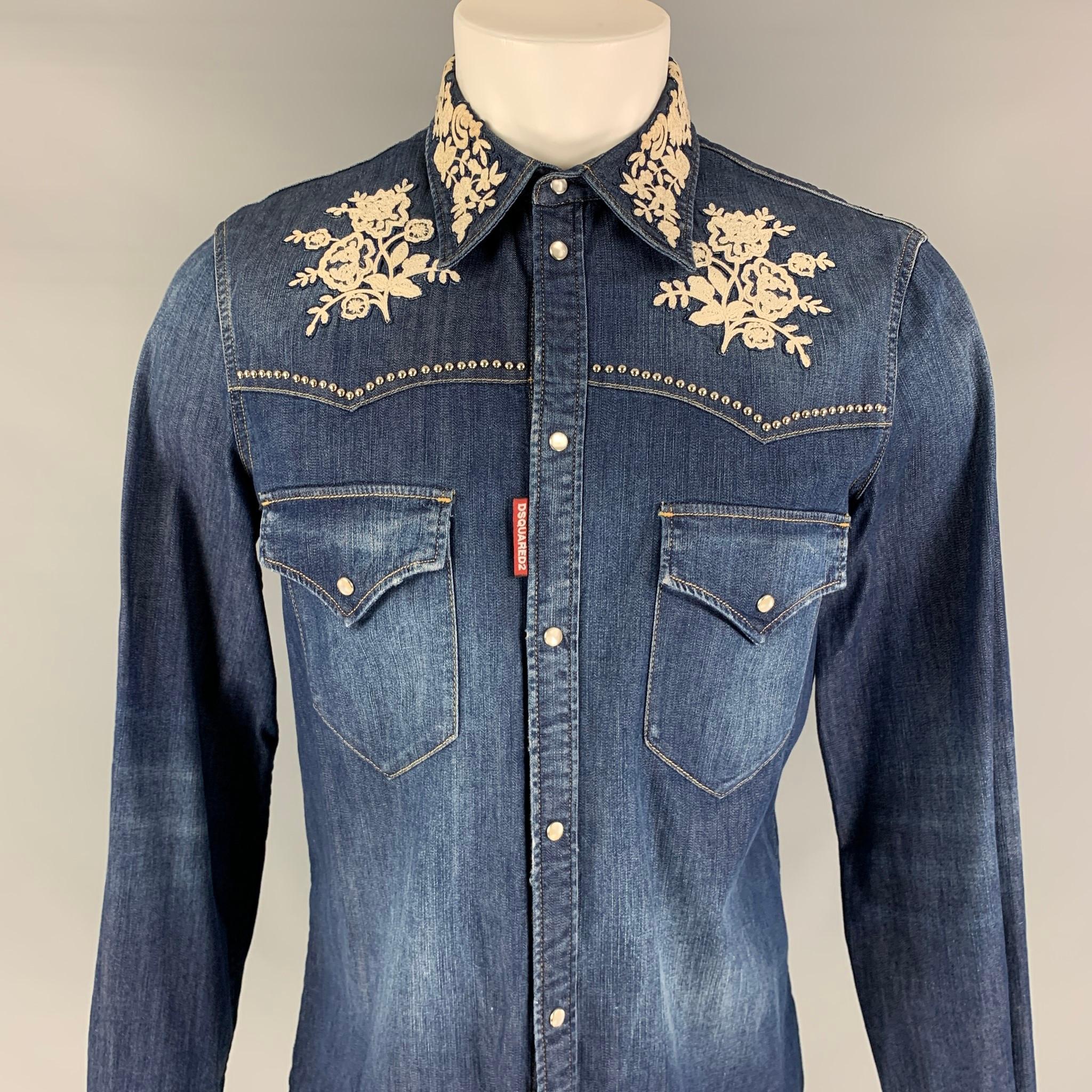 DSQUARED2 long sleeve shirt comes in a indigo denim featuring white floral embroidery details, pointed collar, flap pockets, contrast stitching, and a snap button closure. Made in Italy. 

Excellent Pre-Owned Condition.
Marked: