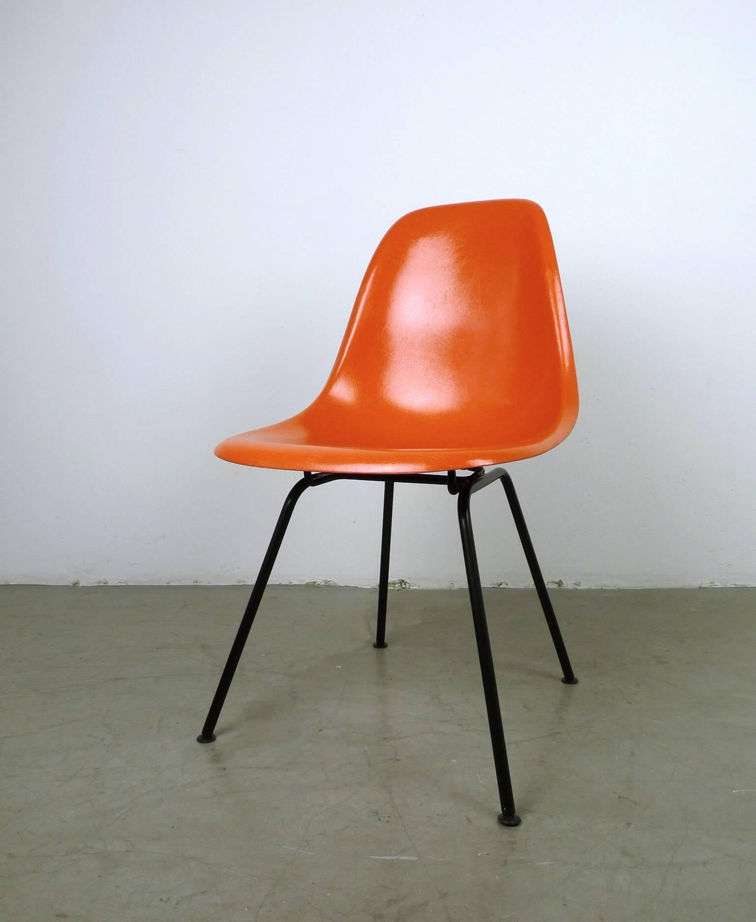 This 'Dining Height Side Chair X-Base' (DSX) with an orange fiberglass seat and a black base was designed by Ray and Charles Eames and produced by Herman Miller in the United States in the 1970s. The chair is in very good condition.
