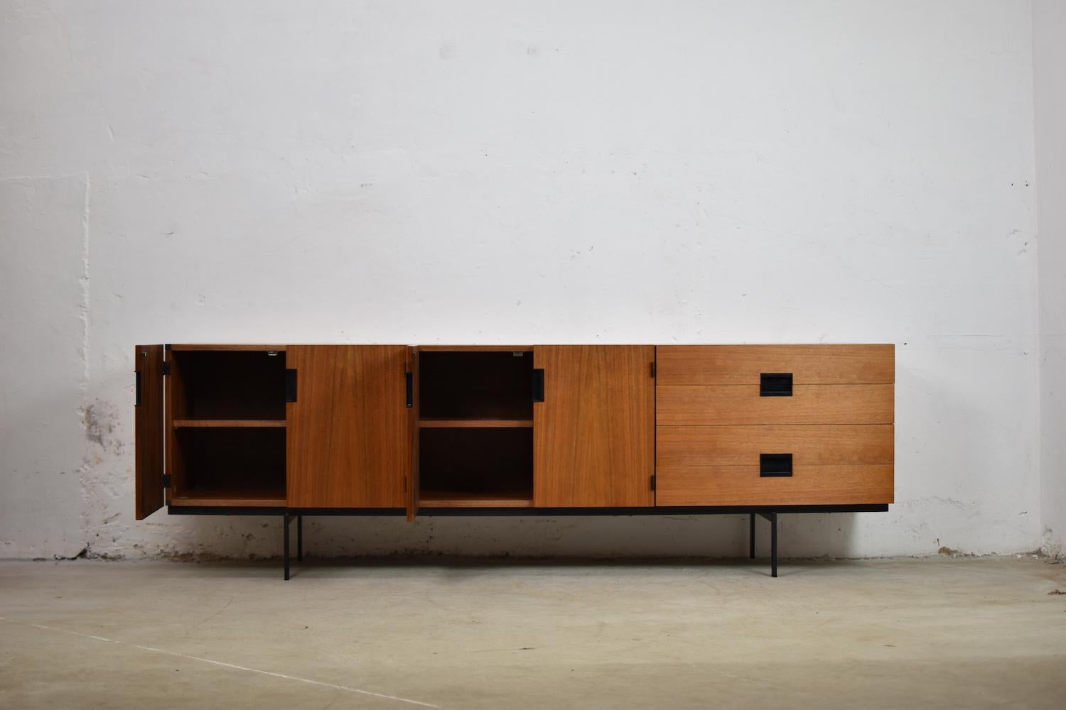 Stunning sideboard by Cees Braakman for UMS Pastoe, The Netherlands 1958, model DU03. This sideboard is made out of teak and features black rectangular handles and a black lacquered metal frame. On the left two storage compartments with shelves, on
