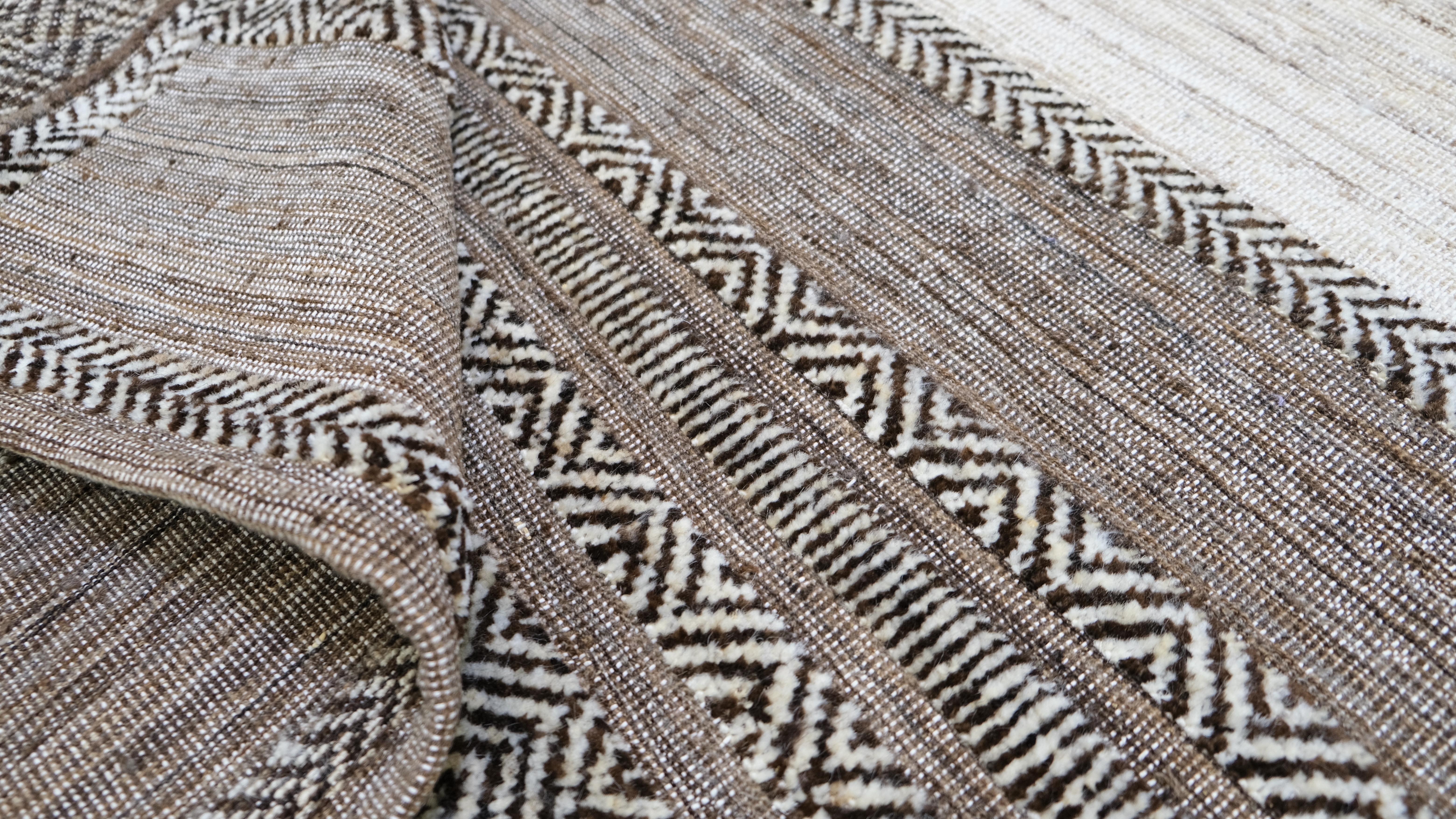 Introduce en tu hogar una sofisticada mezcla de tradición y modernidad con esta exquisita alfombra de lana anudada a mano. Con un diseño minimalista, la alfombra presenta una llamativa composición de rayas en tonos neutros enmarcadas por intrincados