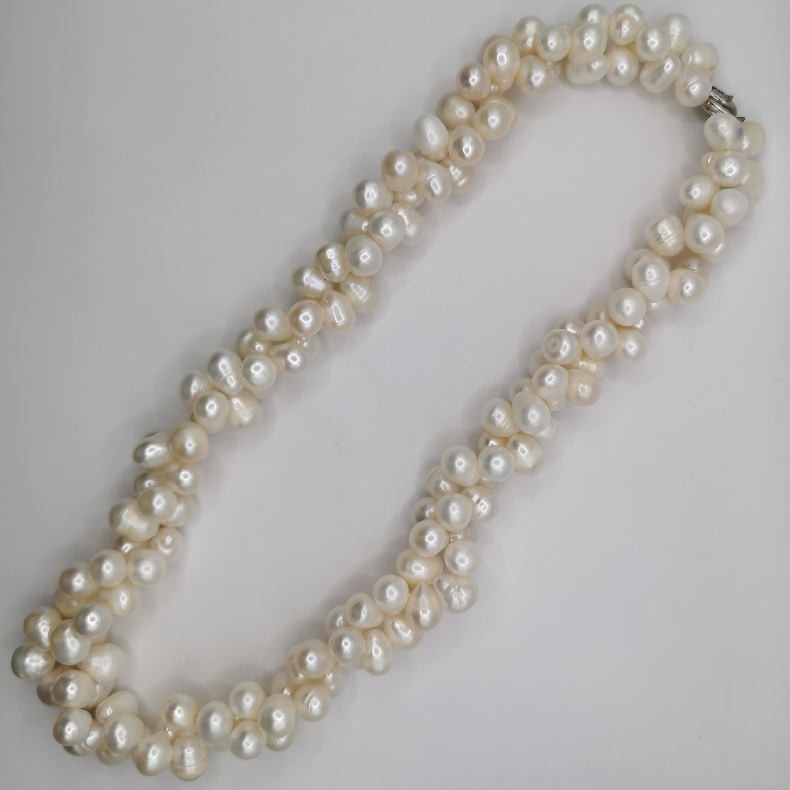 Ce collier de perles blanches baroques de culture d'eau douce à double torsion est une pièce magnifique et élégante qui ne manquera pas d'impressionner. Le collier présente un design unique, avec deux brins torsadés de perles blanches baroques de