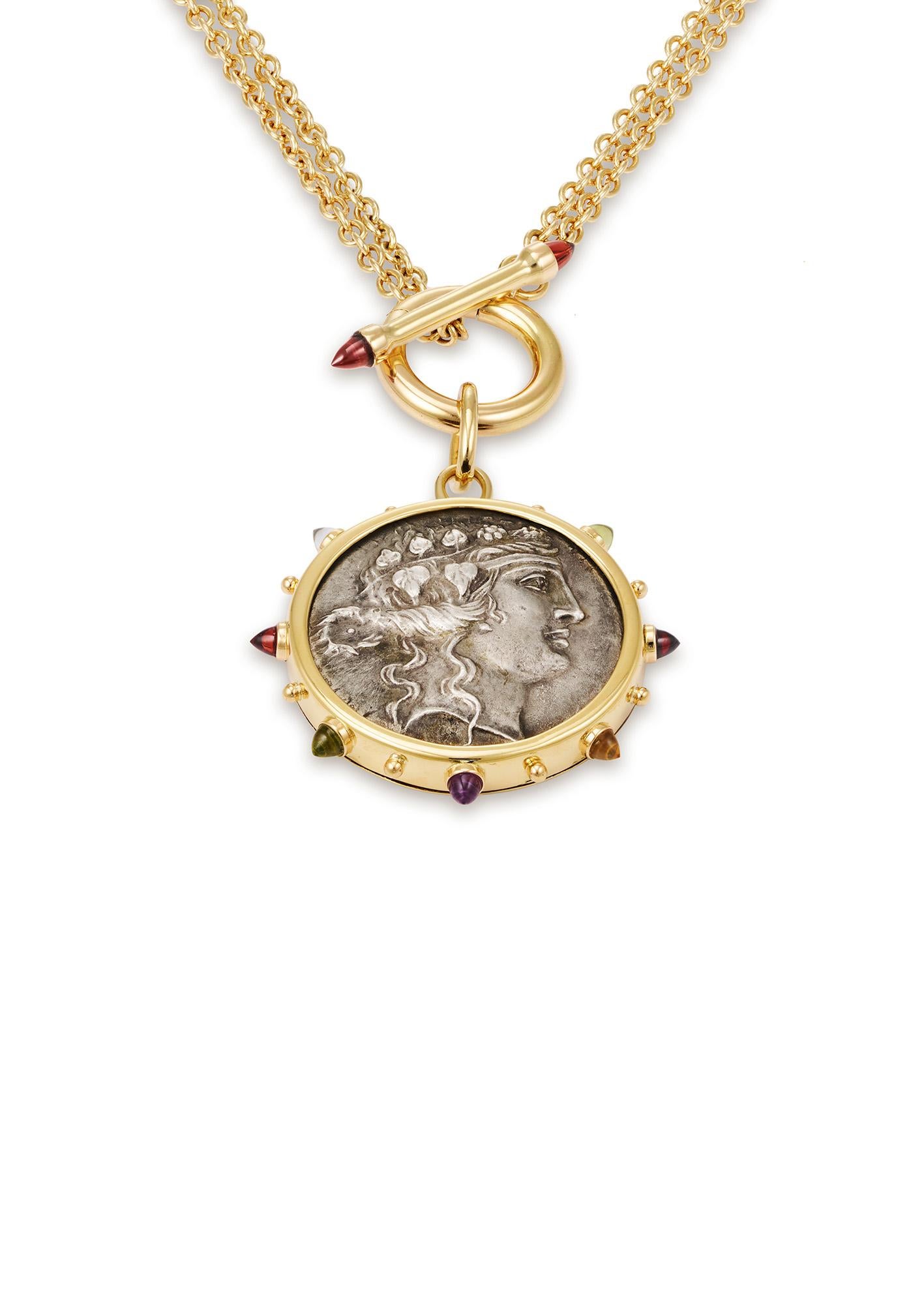 This DUBINI coin necklace from the 'Empires' collection features an authentic silver tetradrachm coin from 189-45 B.C. set in 18K yellow gold with bullet amethyst, garnet, topaz, citrine and peridot cabochons. Paired with a unique rollo chain front