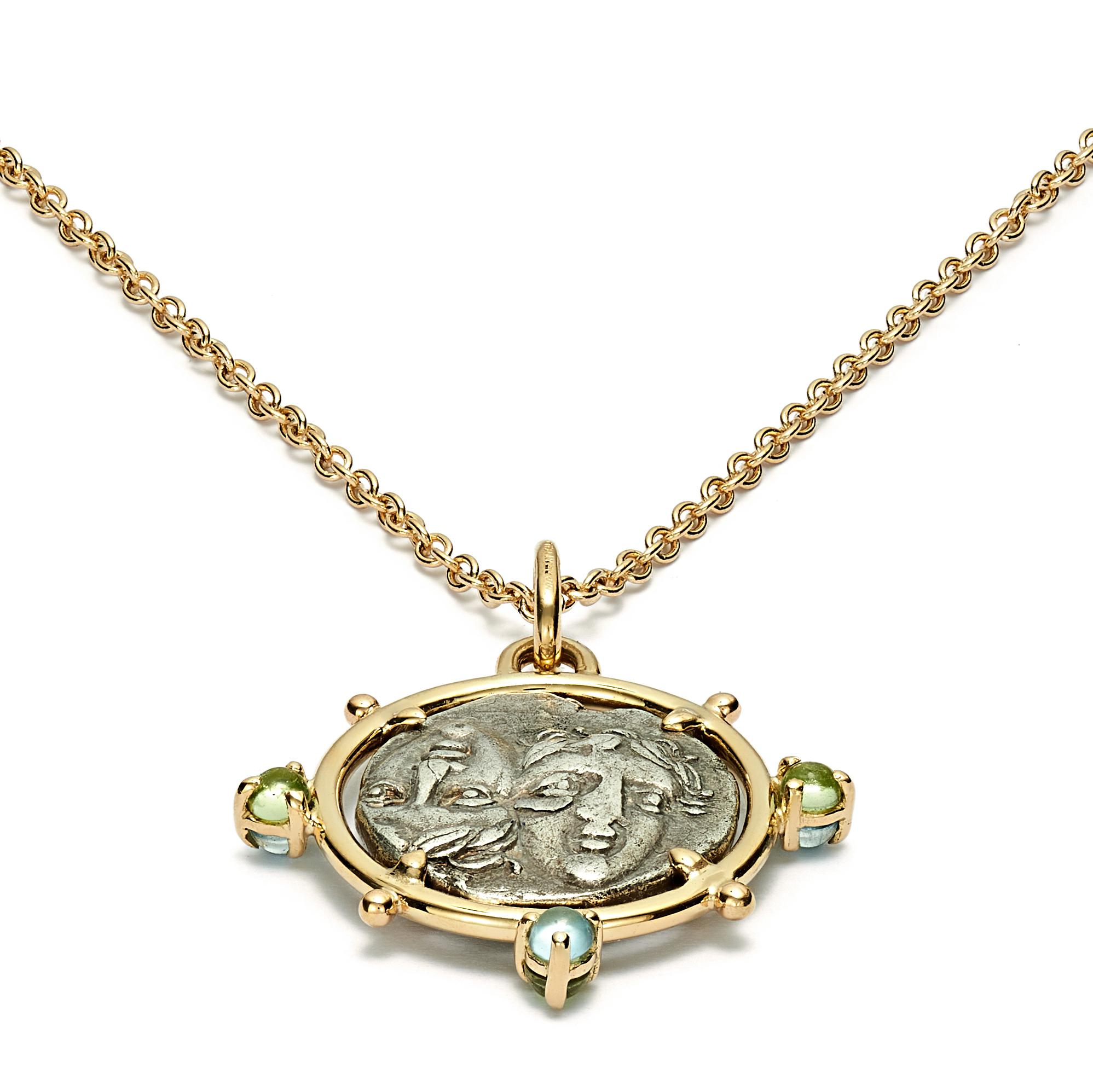 This DUBINI coin necklace from the 'Empires' collection features an authentic silver coin from Istros, Moesia dating circa 4th century B.C. set in 18kt yellow gold with peridot and aquamarine cabochons.

Depicted on the coin: 
Obverse - Two young