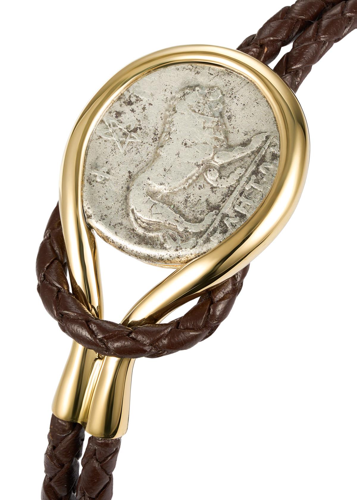 Dieses DUBINI Münzarmband aus der 'Empires' Kollektion zeigt eine authentische Silberdidrachme, die um 300-280 v. Chr. geprägt wurde, gefasst in 18K Gelbgold mit geflochtenem Kalbslederarmband.

AUF DER MÜNZE ABGEBILDET

Vorderseite: Nach rechts