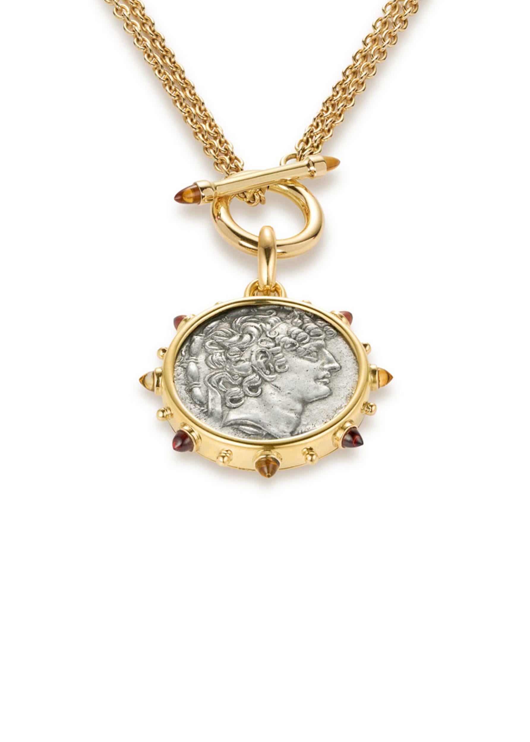 This DUBINI coin necklace from the 'Empires' collection features an authentic silver coin of Philip I Philadelphos circa 95-76 B.C. set in 18k yellow gold with citrine and garnet bullet cabochons. Paired with a unique rollo chain front closing