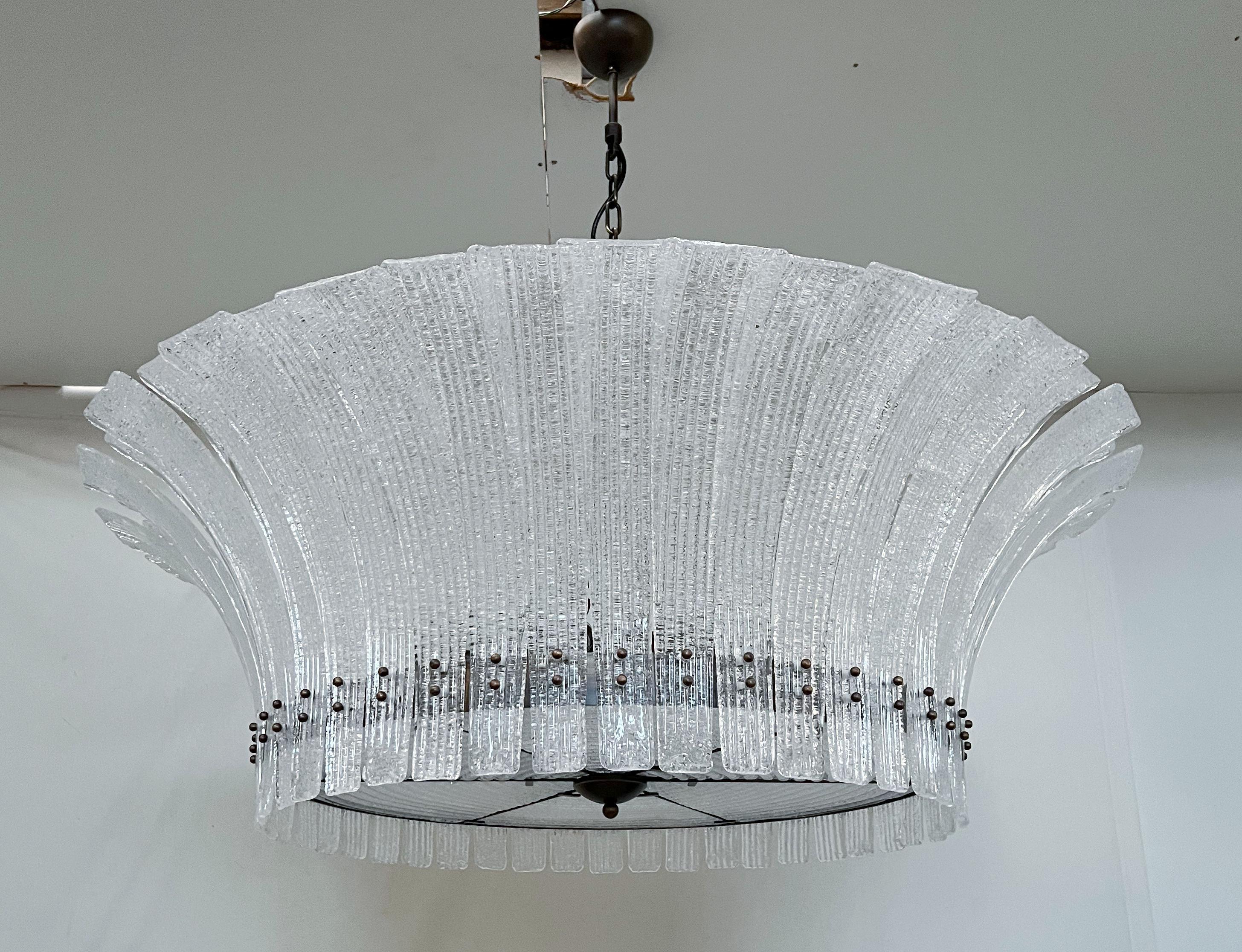 Lampadario moderno italiano con foglie in vetro di Murano trasparente soffiato a mano con effetto granulare con la tecnica della Graniglia, montato su una struttura con finitura bronzata / Made in Italy
12 luci / tipo E26 o E27 / max 60W