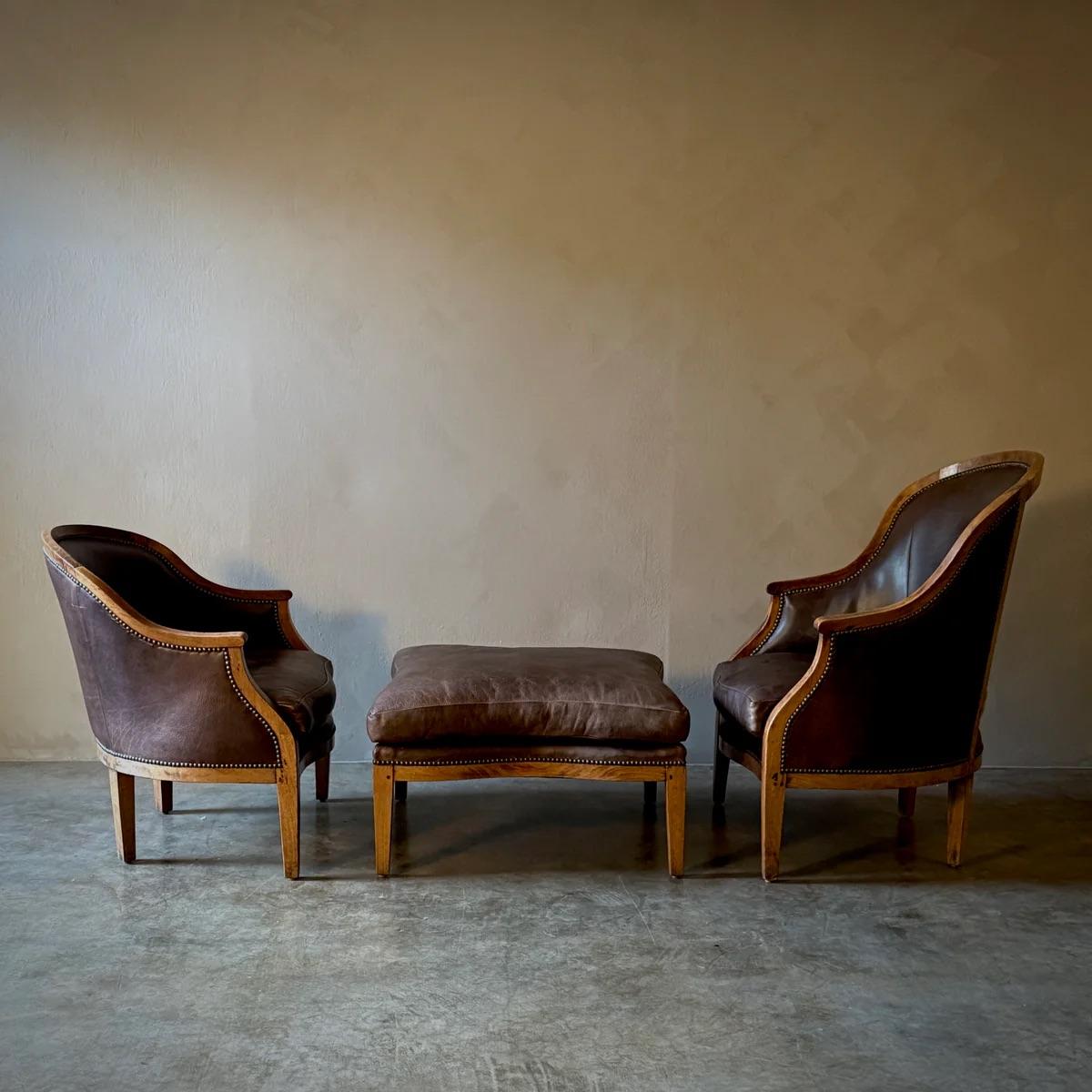 Cet ensemble de chaises Eleg et l'ottoman assorti, fabriqués en noyer riche et recouverts de cuir souple, exsudent l'élégance et l'histoire. Chaque chaise, dont la taille diffère subtilement, suggère un design traditionnel 