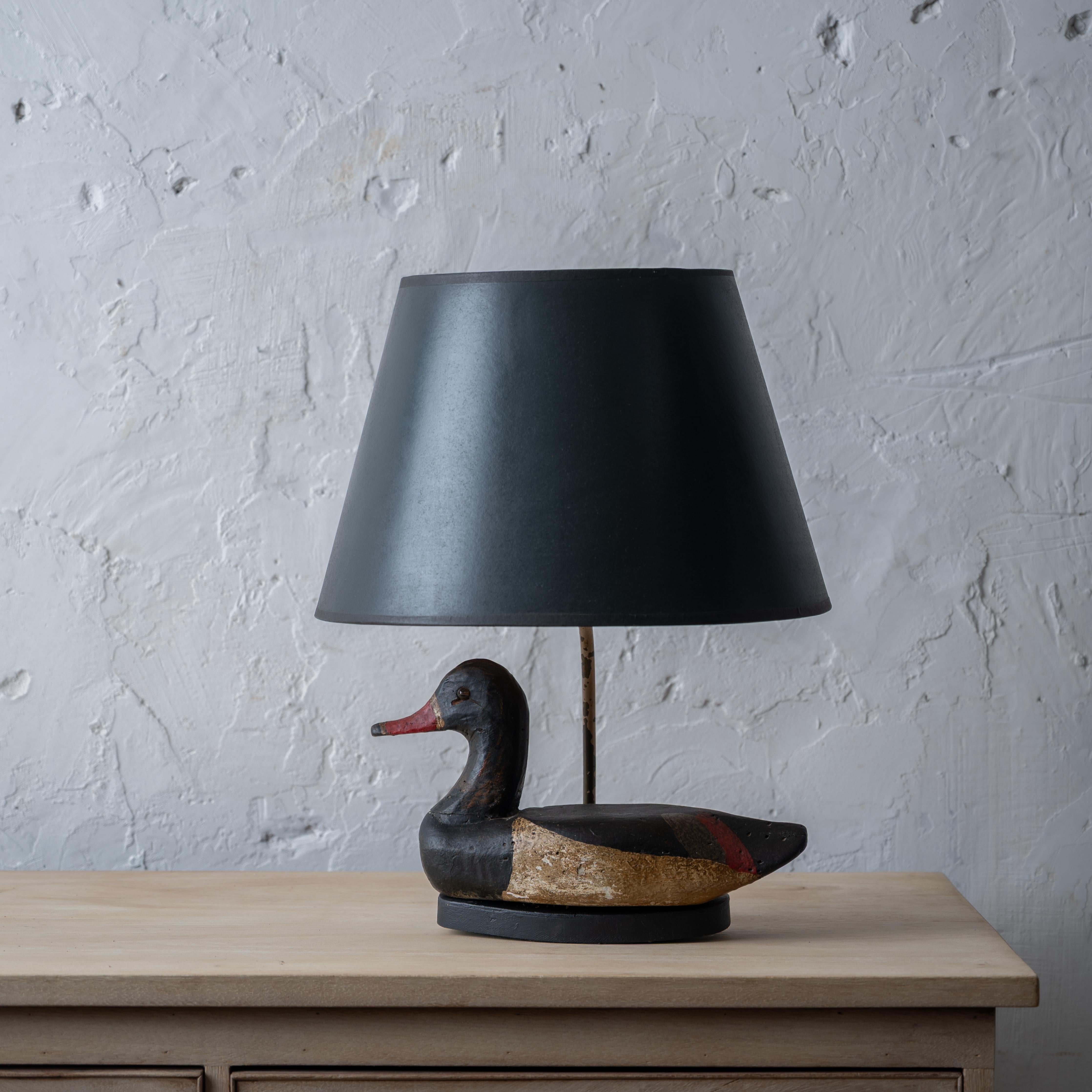 An antique duck decoy mounted as a lamp in dark green paper shade.



12 ½ inches wide by 6 inches deep by 18 ¼ inches tall;

shade: 14 inches wide by 9 ½ inches tall



