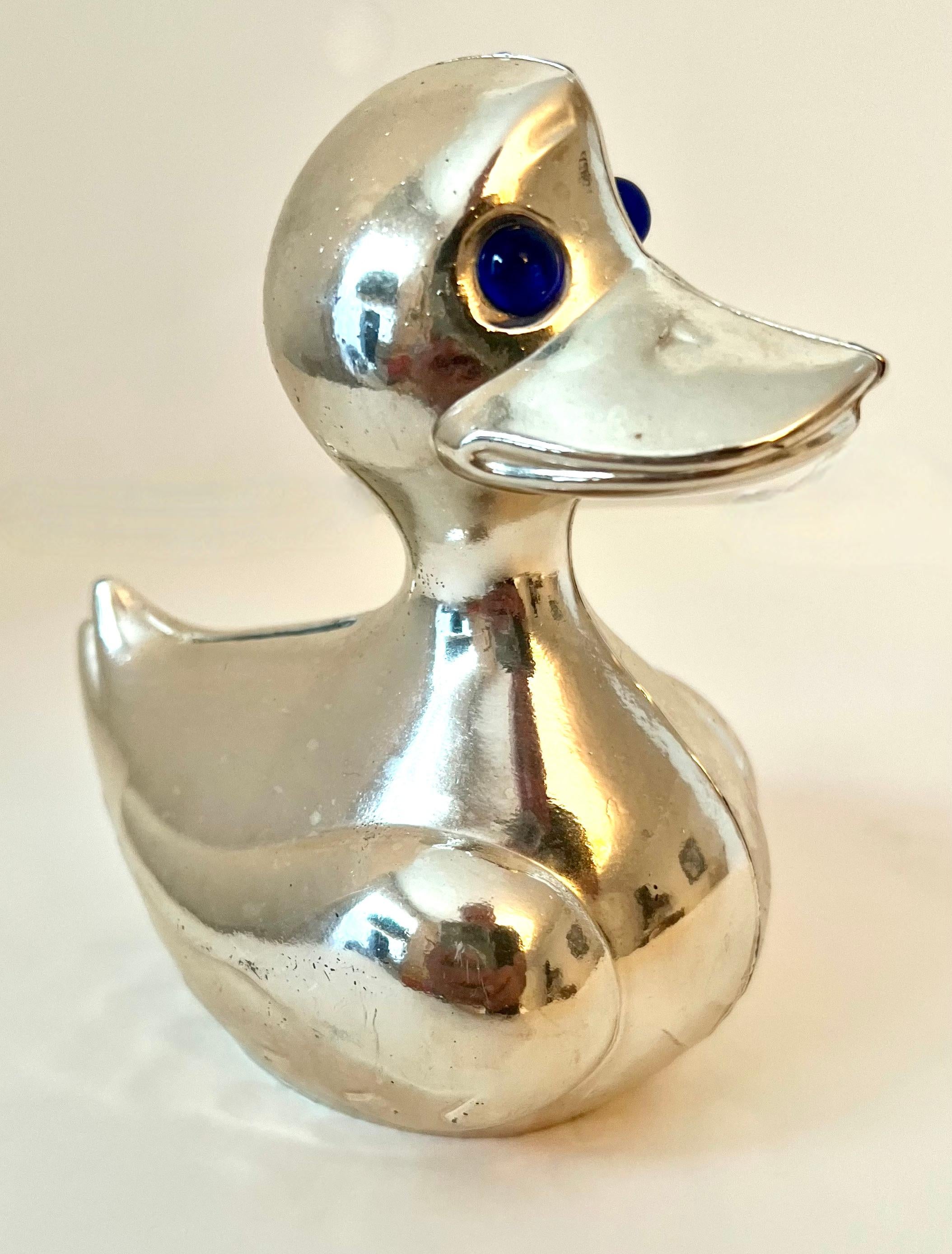 a vintage silver tone bank in the shape of a duck.  The piece is very cute with blue glass eyes

The perfect Baby Gift or decorative piece for a Childs room or whimsical stated room,