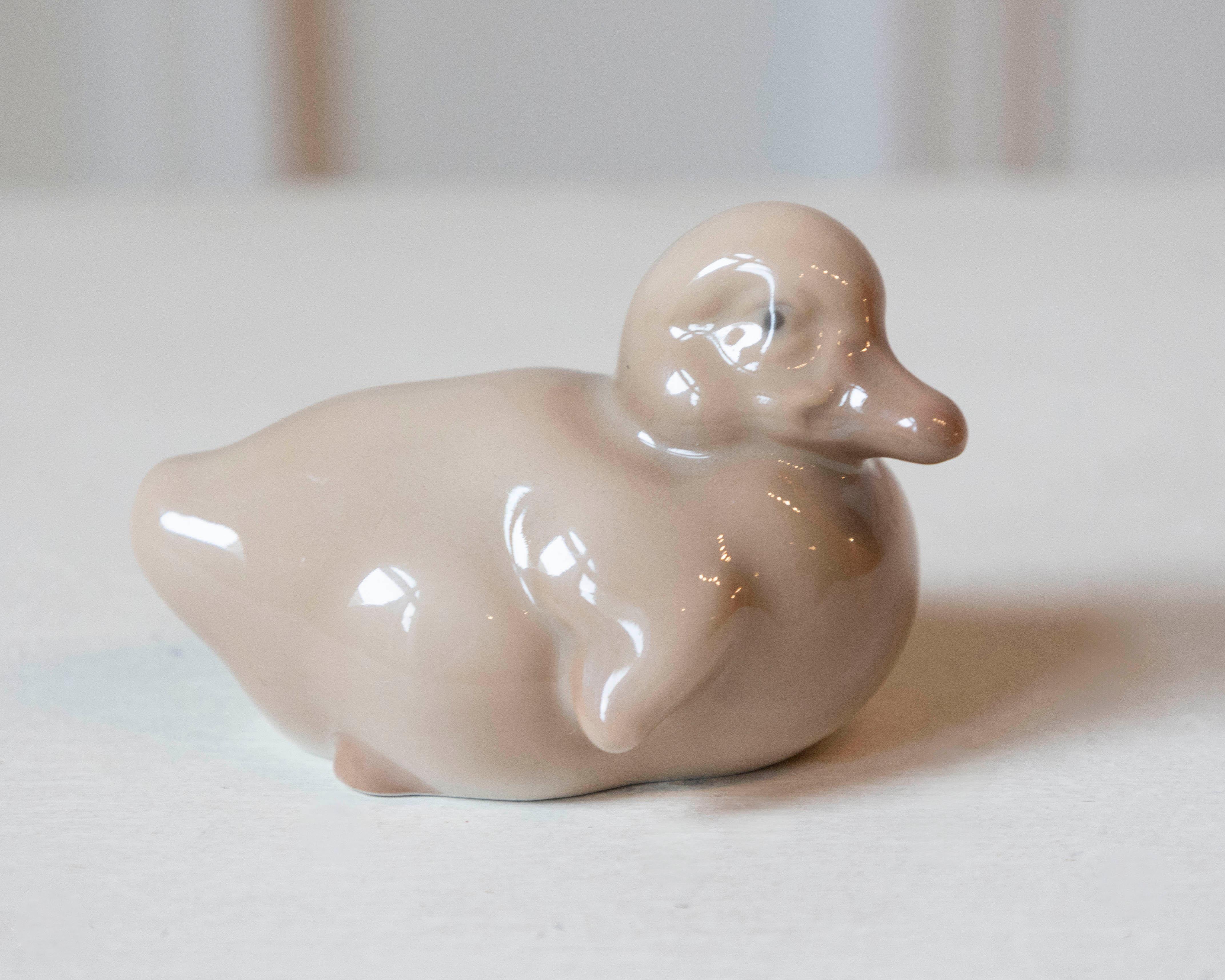 A charming porcelain duckling by Royal Copenhagen, renowned for its exceptional Danish craftsmanship and delicate artistry. This finely modeled figure captures the gentle form and serene expression of a young duck, rendered in the brand’s signature