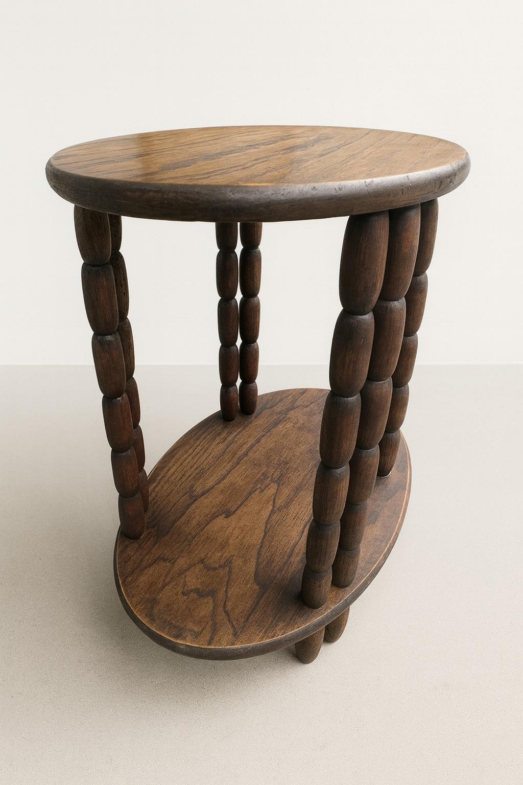 This compact oval side table draws clear inspiration from the bold, sculptural forms associated with Charles Dudouyt, a renowned French designer active in the 1930s and 1940s. Known for his use of robust woods, geometric balance, and rhythmic
