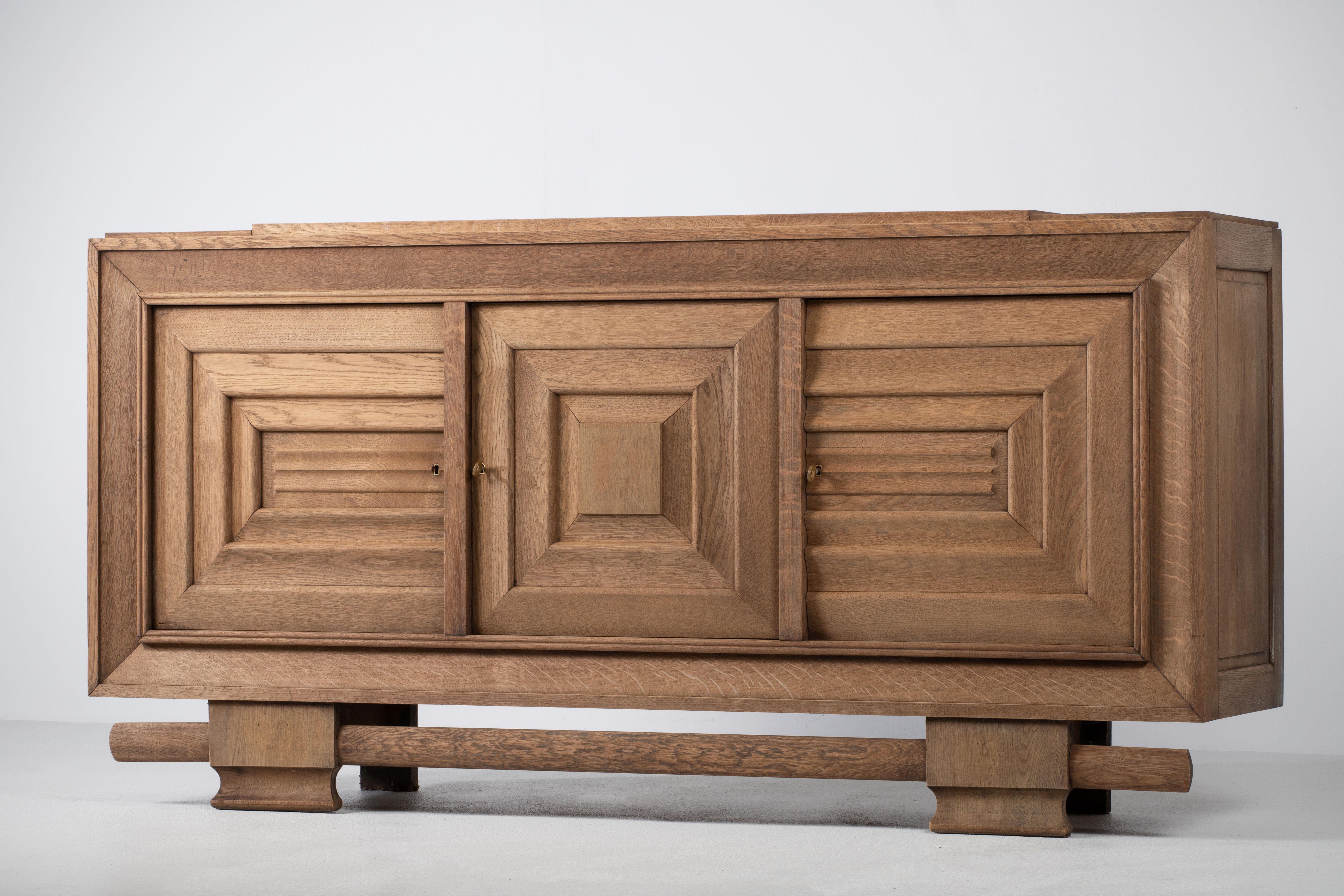 Credenza, solid oak, France, 1940s, attributed to Charles Dudouyt.
Large Art Deco Brutalist sideboard. 
The credenza consists of three storage facilities and covered with very detailed designed door panels. 
The refined wooden structures on the