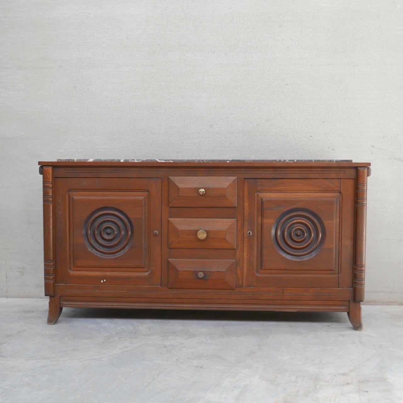 A stylish oak and marble sideboard/credenza. 

France, c1930s. 

In the manner of Dudouyt. 

Stylish concentric rings to each door. 

Generally good condition, some wear commensurate with age. The marble top is a particularly attractive