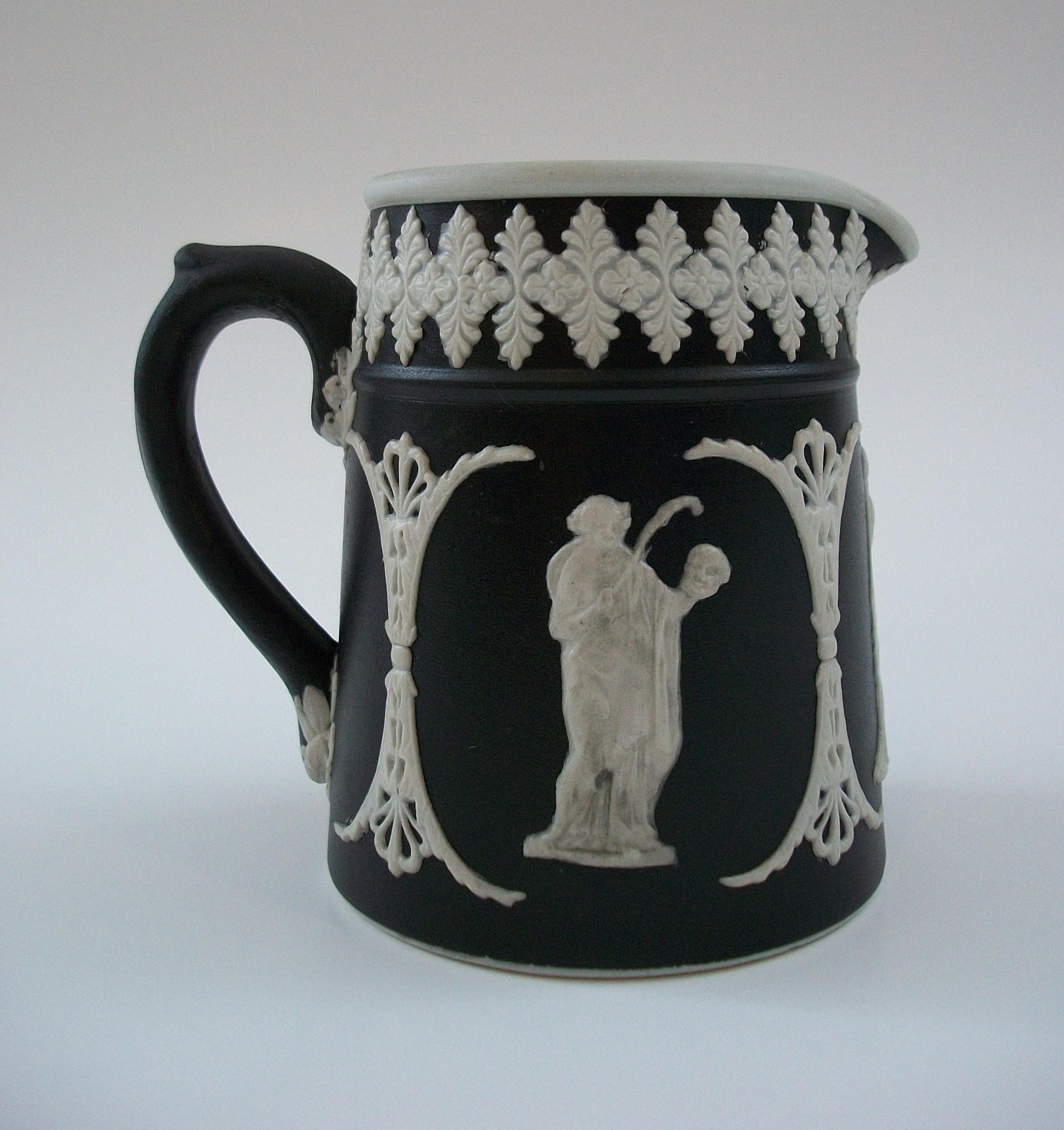 DUDSON BROTHERS - Antique black and white Jasperware ceramic pitcher or creamer - featuring three Neoclassical draped figures between fretwork columns and a leaf border to the top rim - white glazed interior - signed / stamped on the base - United