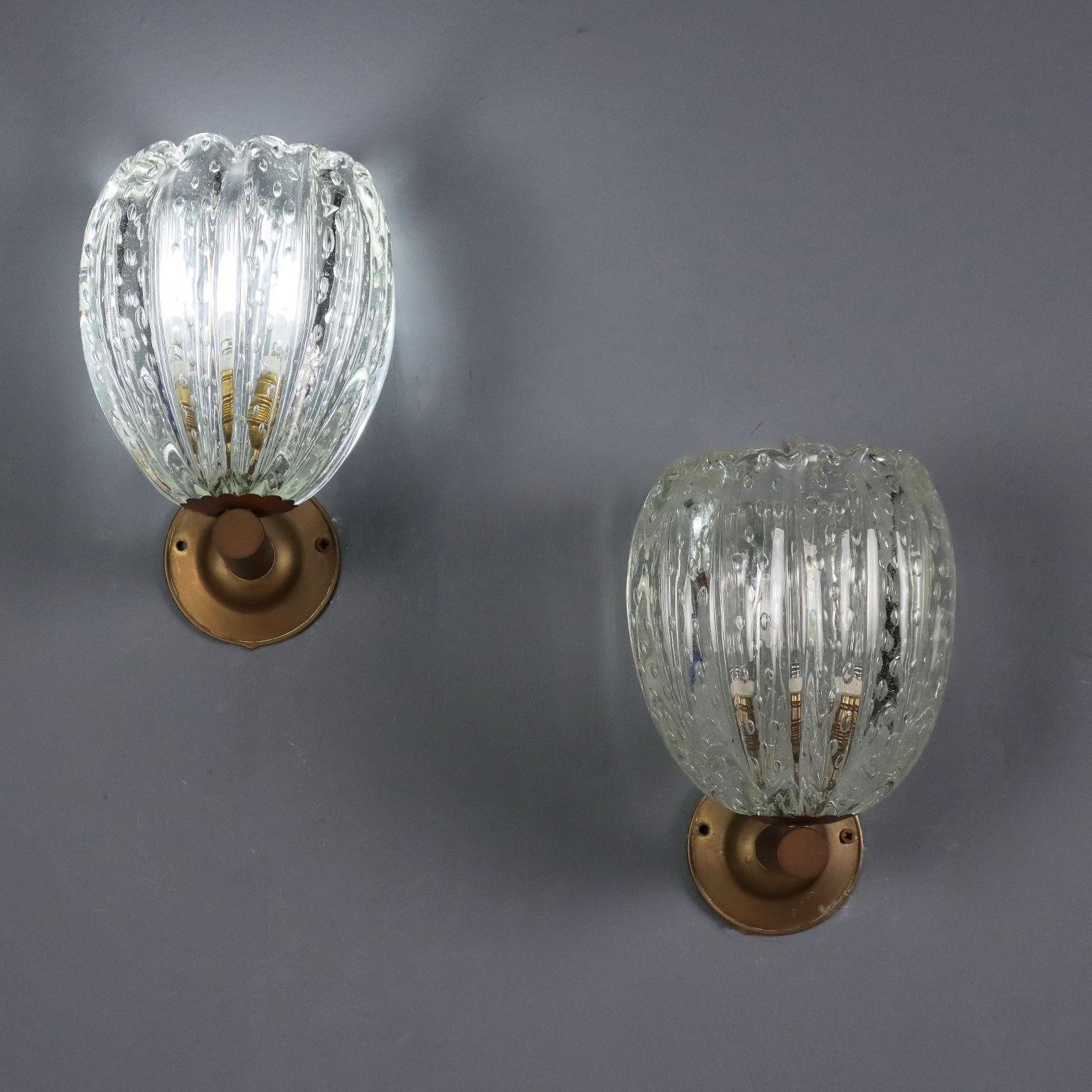 Coppia di eleganti applique di manifattura italiana del XX secolo con attacco in ottone e diffusore in vetro di Murano lavorato. 