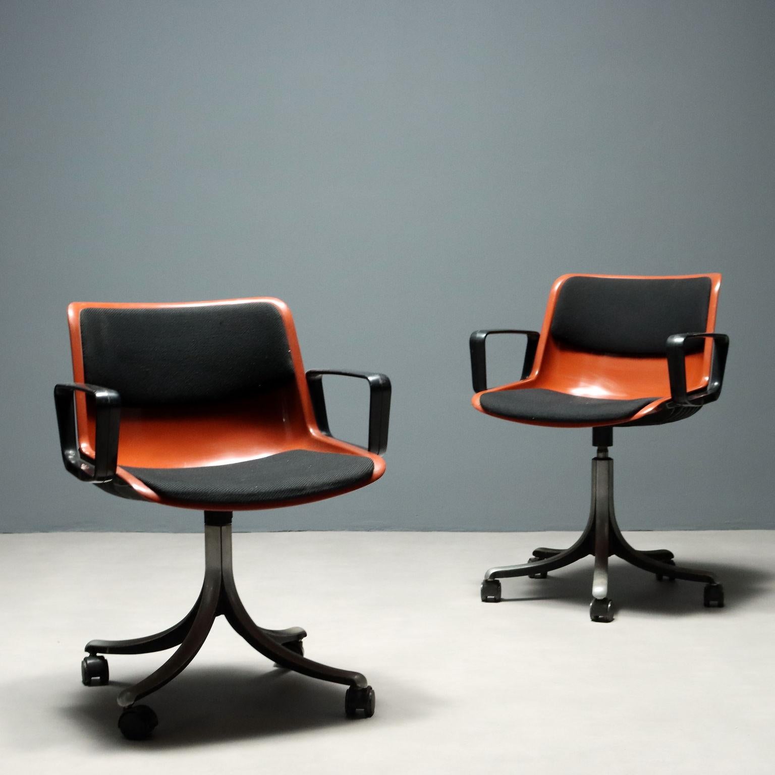 Paire de chaises de bureau avec coque en plastique orange, assise et dossier avec rembourrage en mousse et revêtement en tissu noir, pieds en métal à quatre branches avec roulettes. La marque du fabricant est présente.