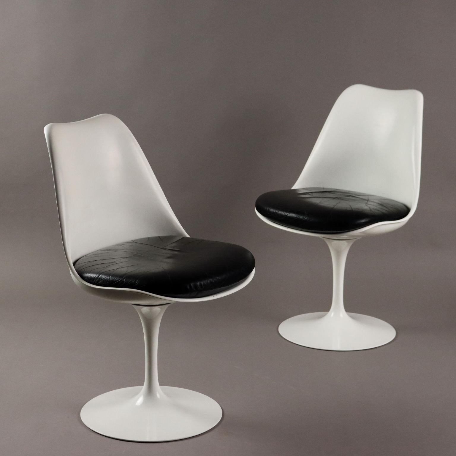 Coppia di iconiche sedie modello 'Tulip' con base in fusione di alluminio, scocca in materiale plastico, cuscino in espanso con rivestimento in pelle originale del periodo.