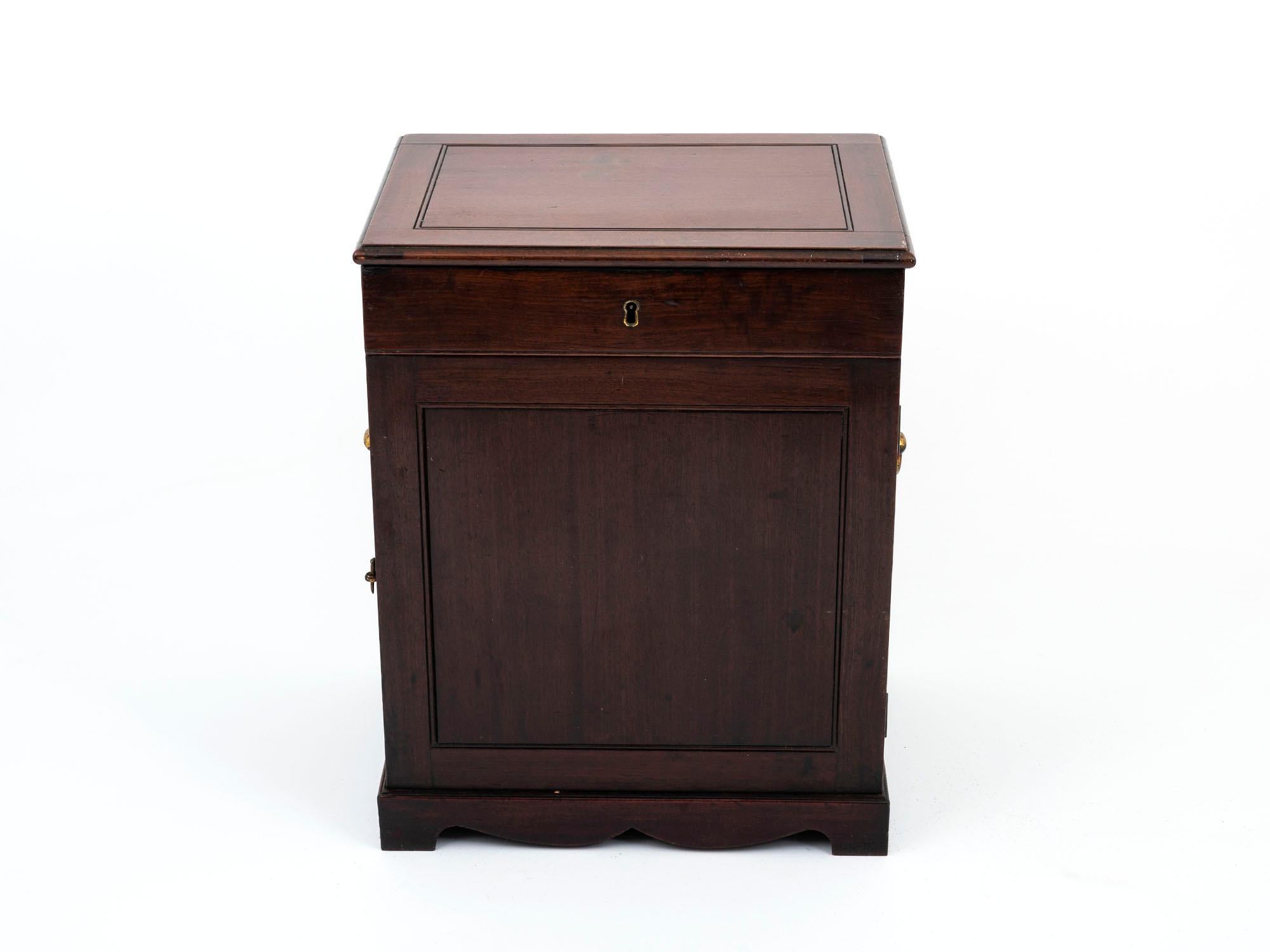 Standing on a wonderfully shaped plinth with brass handles, door latches and a key profile is this Duke of York Apothecary Cabinet in Mahogany.

When the lid is closed, the front and rear doors are secured. Lifting the lid reveals an interior