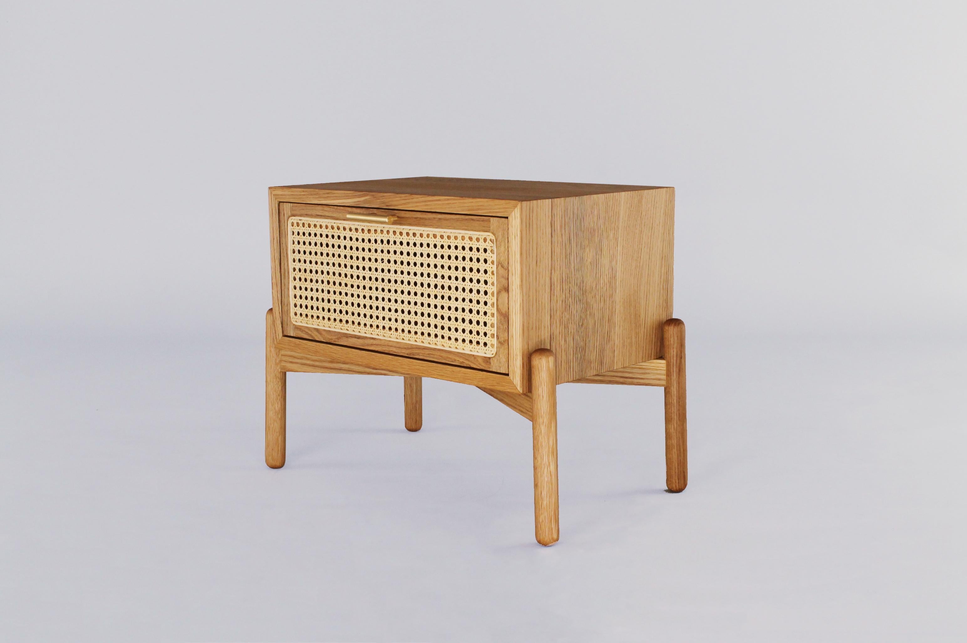 A fresh and elegant nightstand made of oak with woven wicker front drawer.  The wicker caning and carpentry are made by Mexican artisans. This bedside table has a brass handle that fuses with its Mexican contemporary style giving it a touch of
